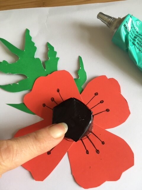 Gluing a bottle top onto a paper poppy