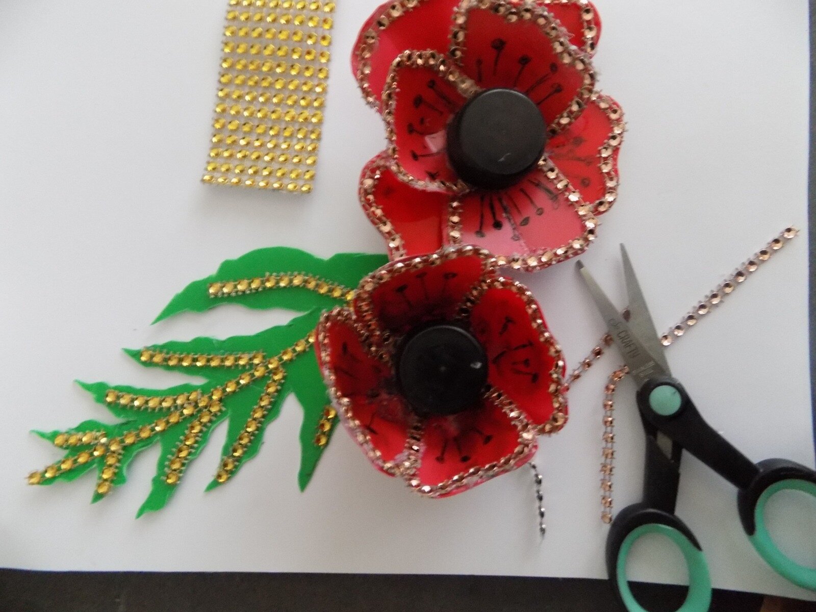 Sequins, scissors and a poppy made from recycled plastic materials
