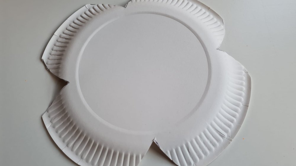 The reverse of a A white paper plate cut into a poppy shape
