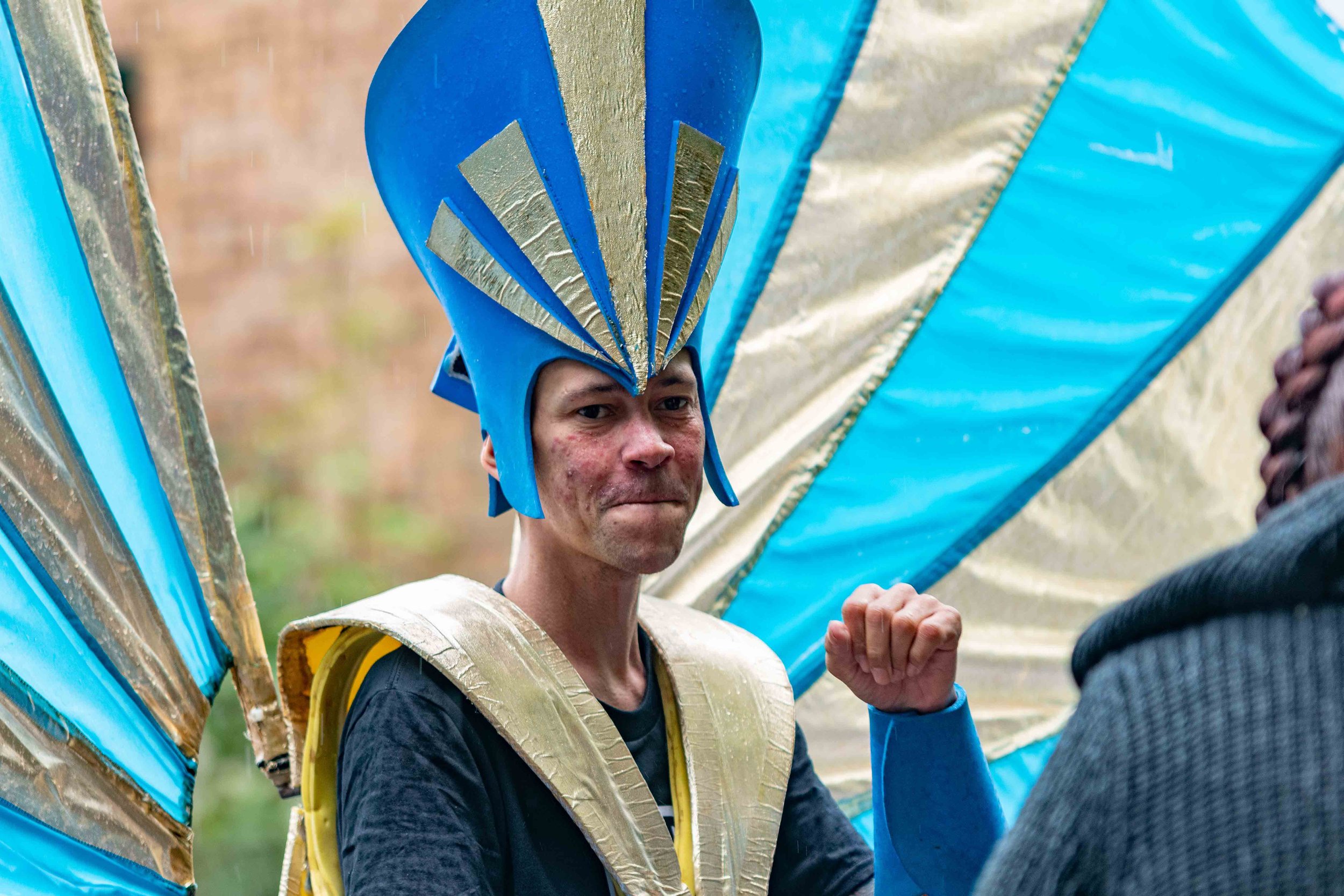 Close up of member of Tokko and Pride In Luton carnival group wearing a gold and blue costume and smiling to camera
