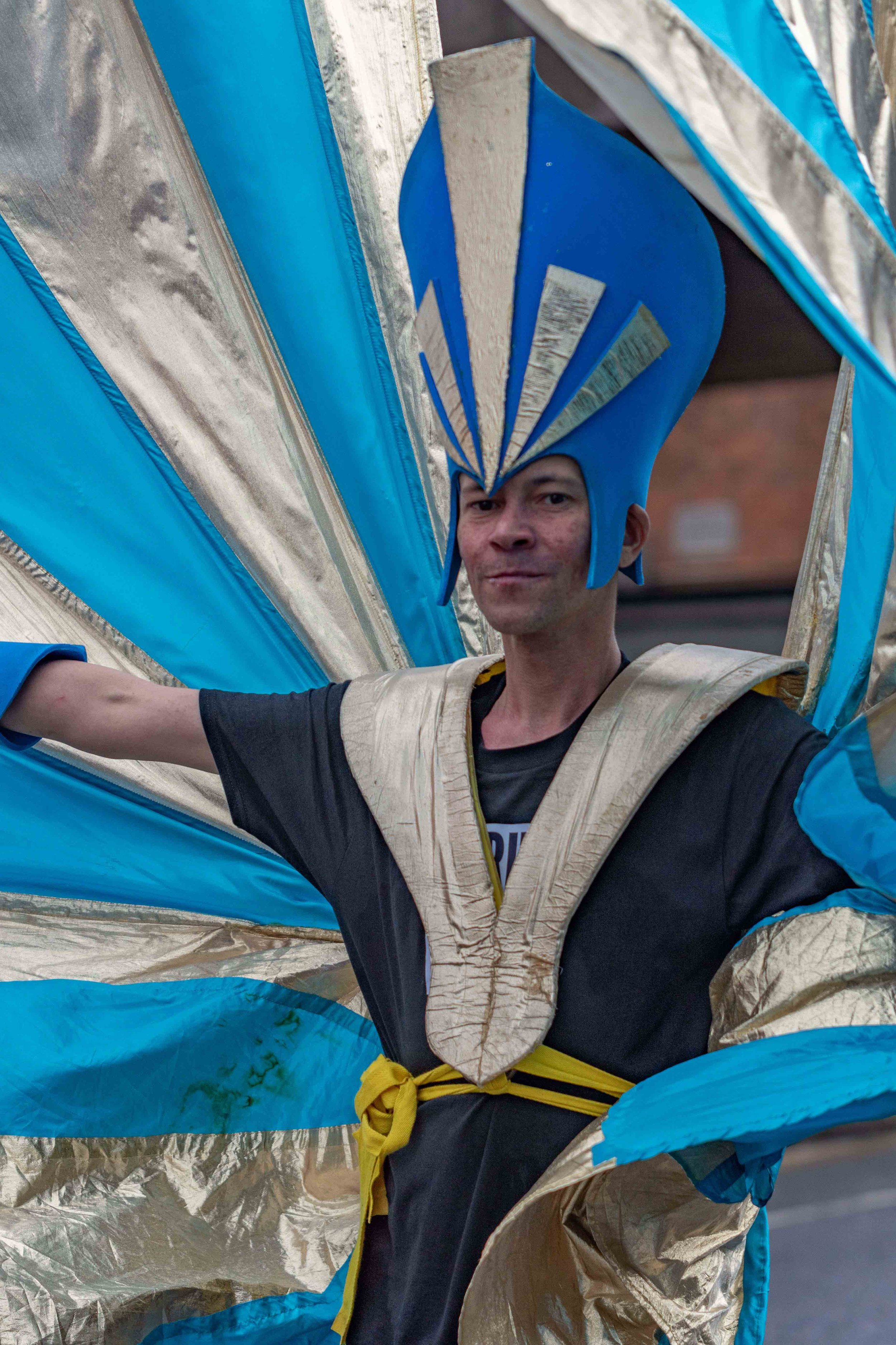 Close up of member of Tokko and Pride In Luton carnival group wearing a gold and blue costume and smiling to camera