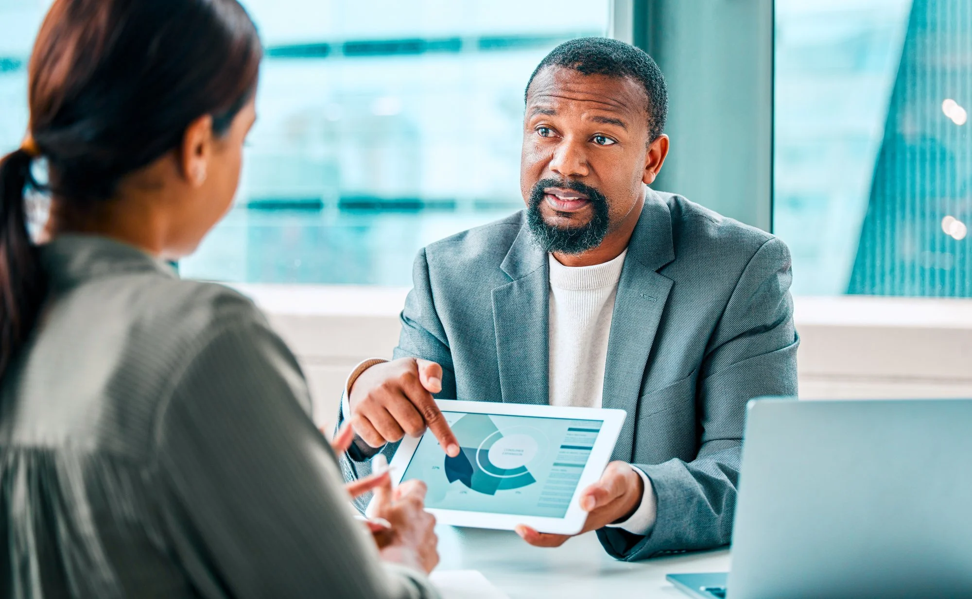 Manager points to a cost chart on a tablet while walking a colleague through the business case for a leadership development program