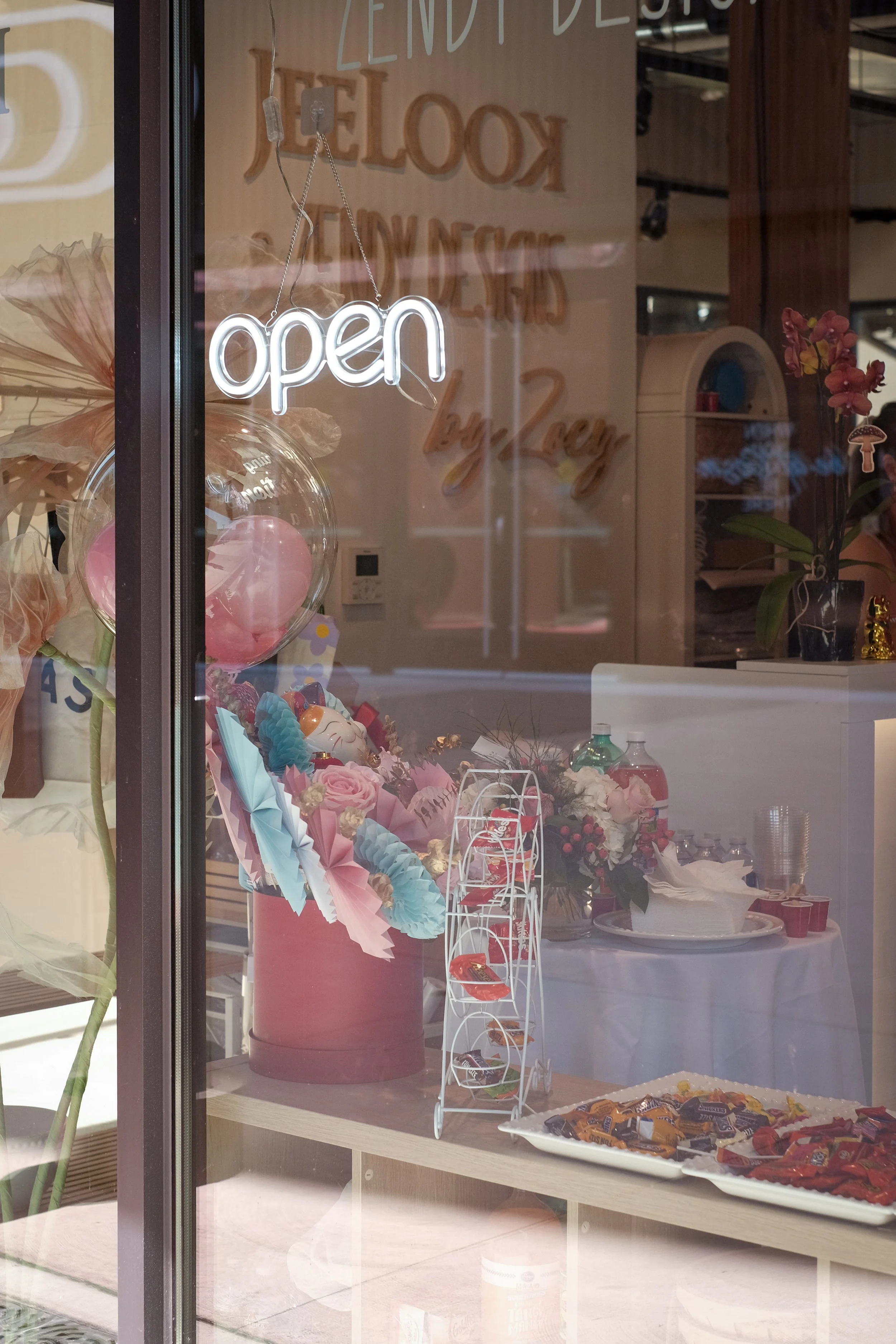 Neon sign on glass window that reads 'open' with decor and snacks visible inside the store.