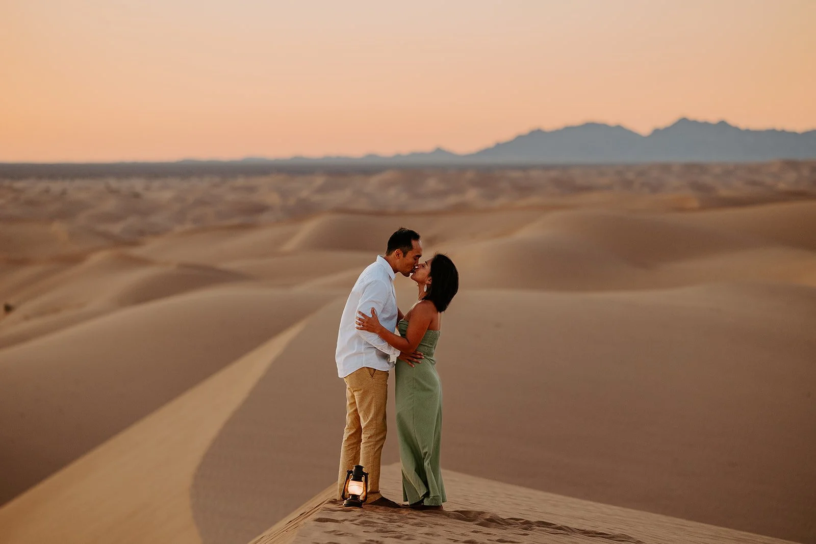 Couple kissing atop a dune at Hugh T. Osborne Lookout in the Imperial Sand Dunes during sunrise engagement photos