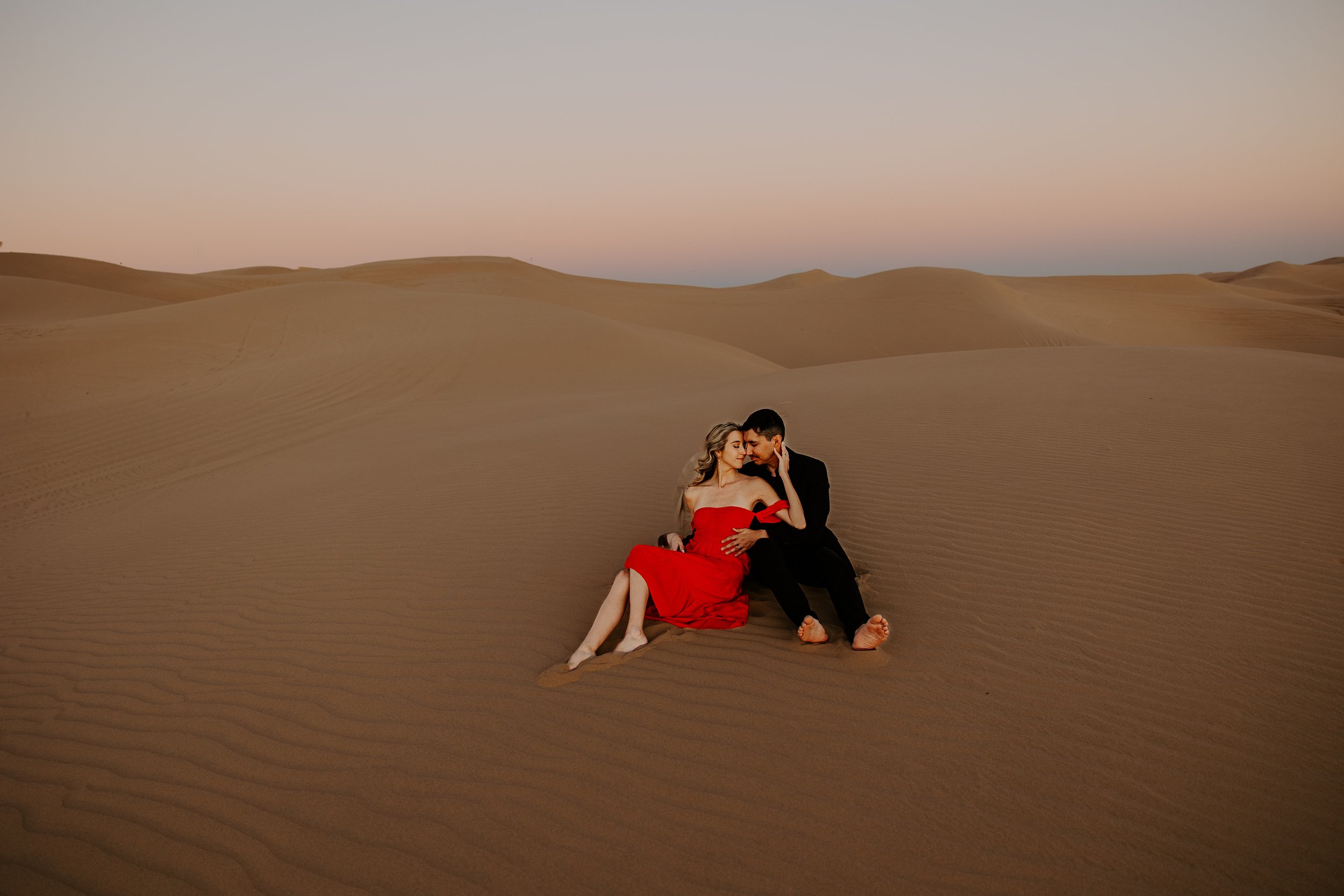 Couple sitting together on a quiet sand dune during sunset in the desert