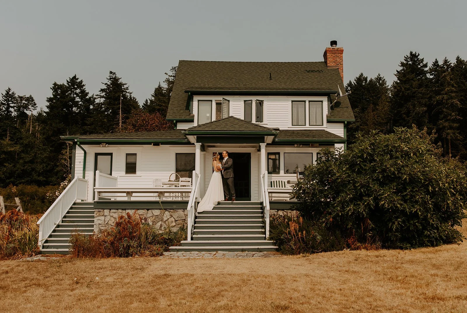 Bride and groom embracing outside coastal vacation rental during San Juan Island elopement.