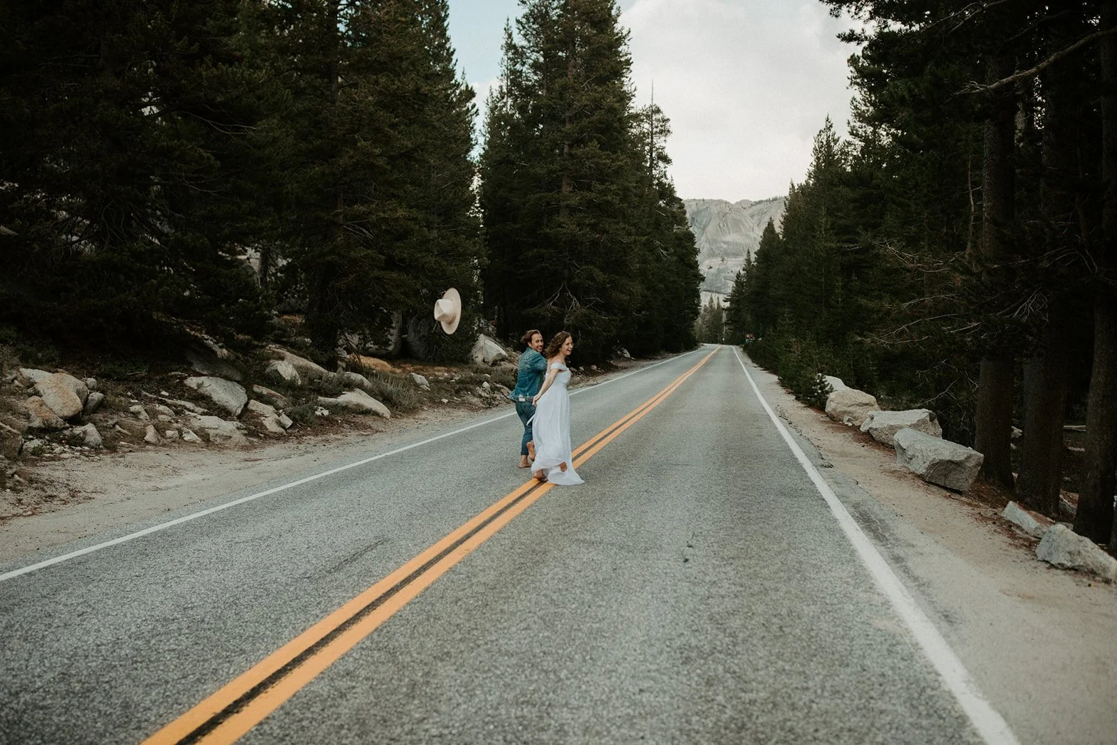 A couple laughing as a hat blows away during their elopement