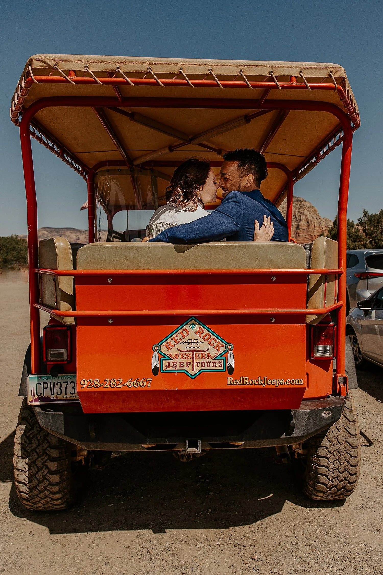 Colleen and Damon sitting in the back of a red jeep on their Red Rock Western Jeep Tour.