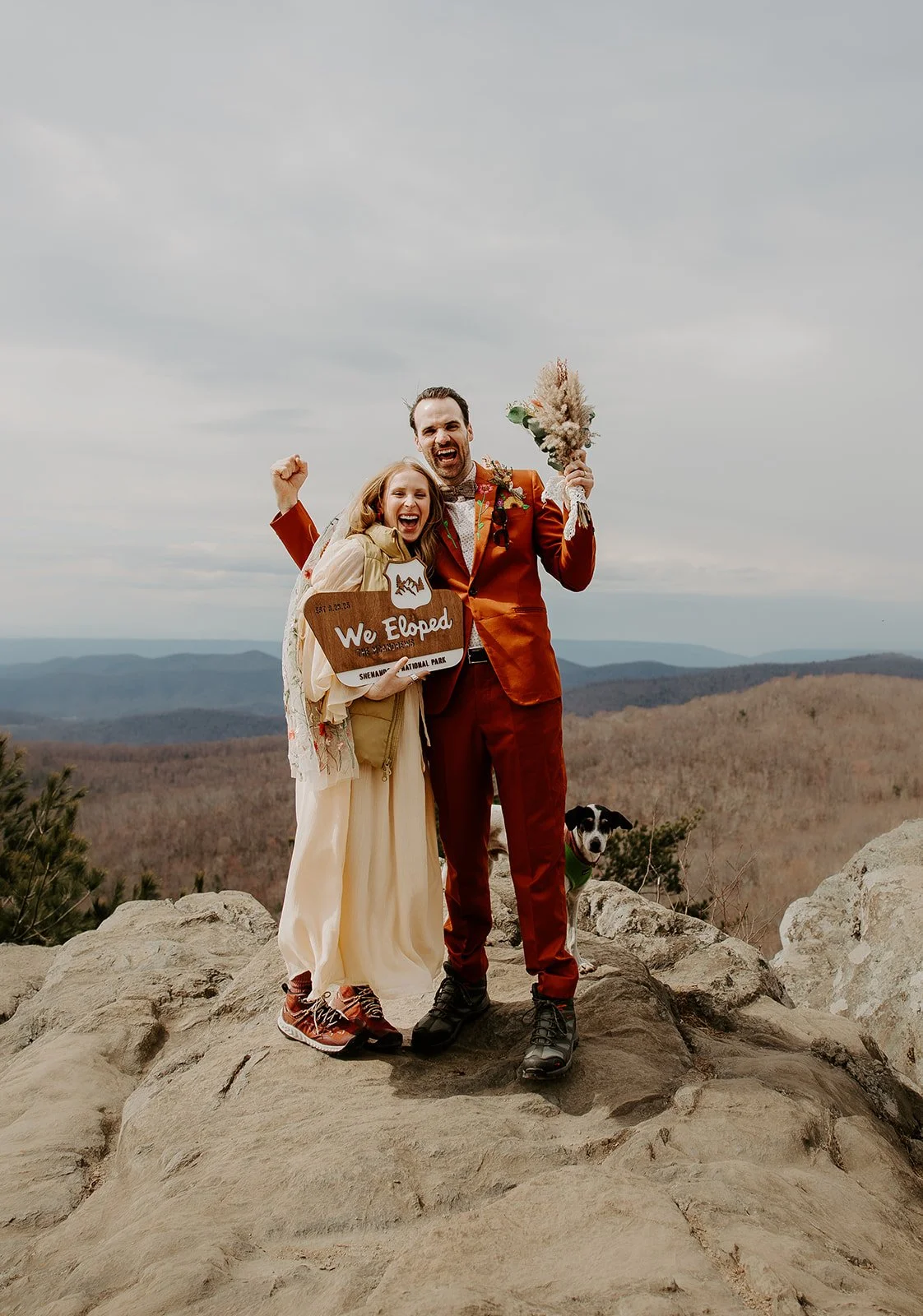 Couple celebrating their elopement with a sign on a scenic mountain overlook
