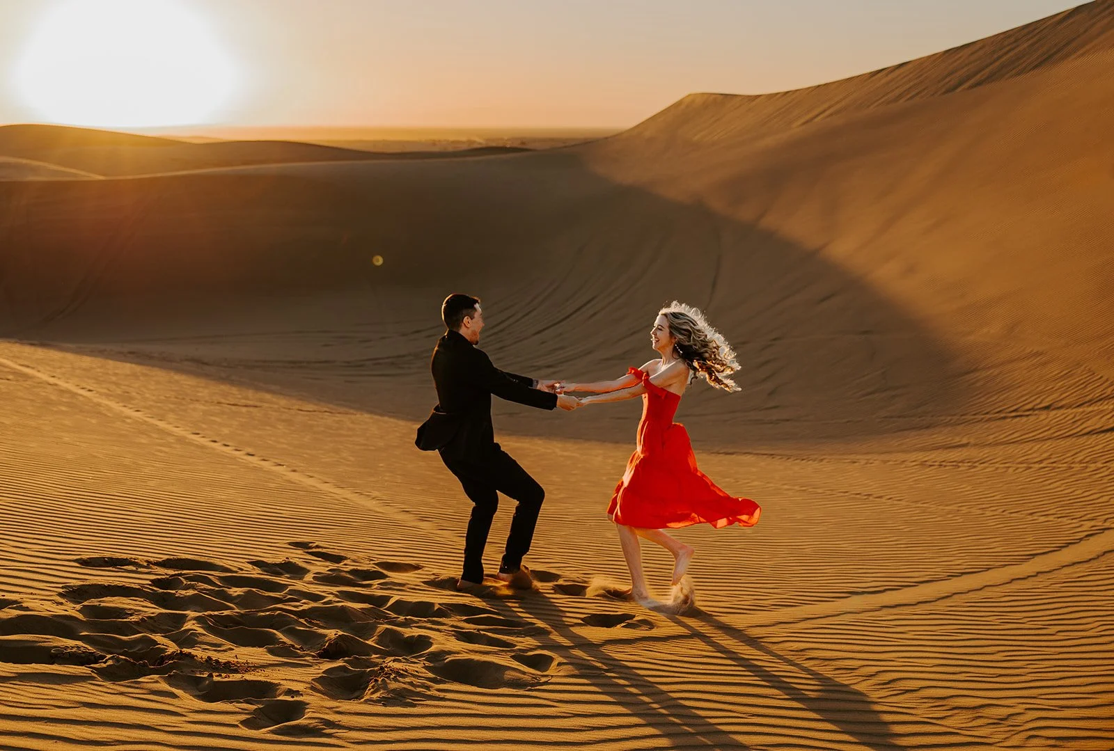 Couple dancing together on golden sand dunes during sunset
