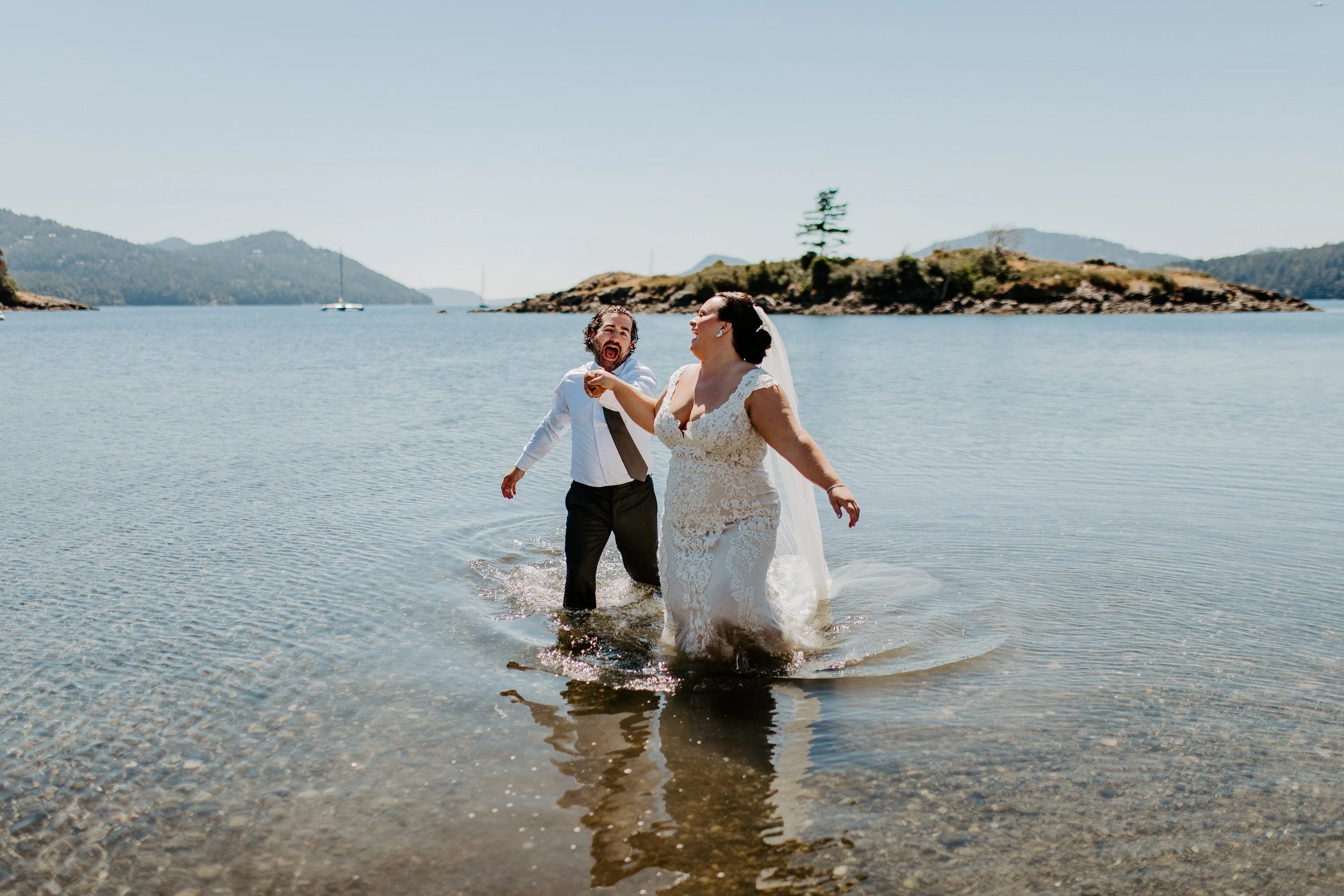Newlyweds running into the water on the beach at Water’s Edge at The Outlook Inn.