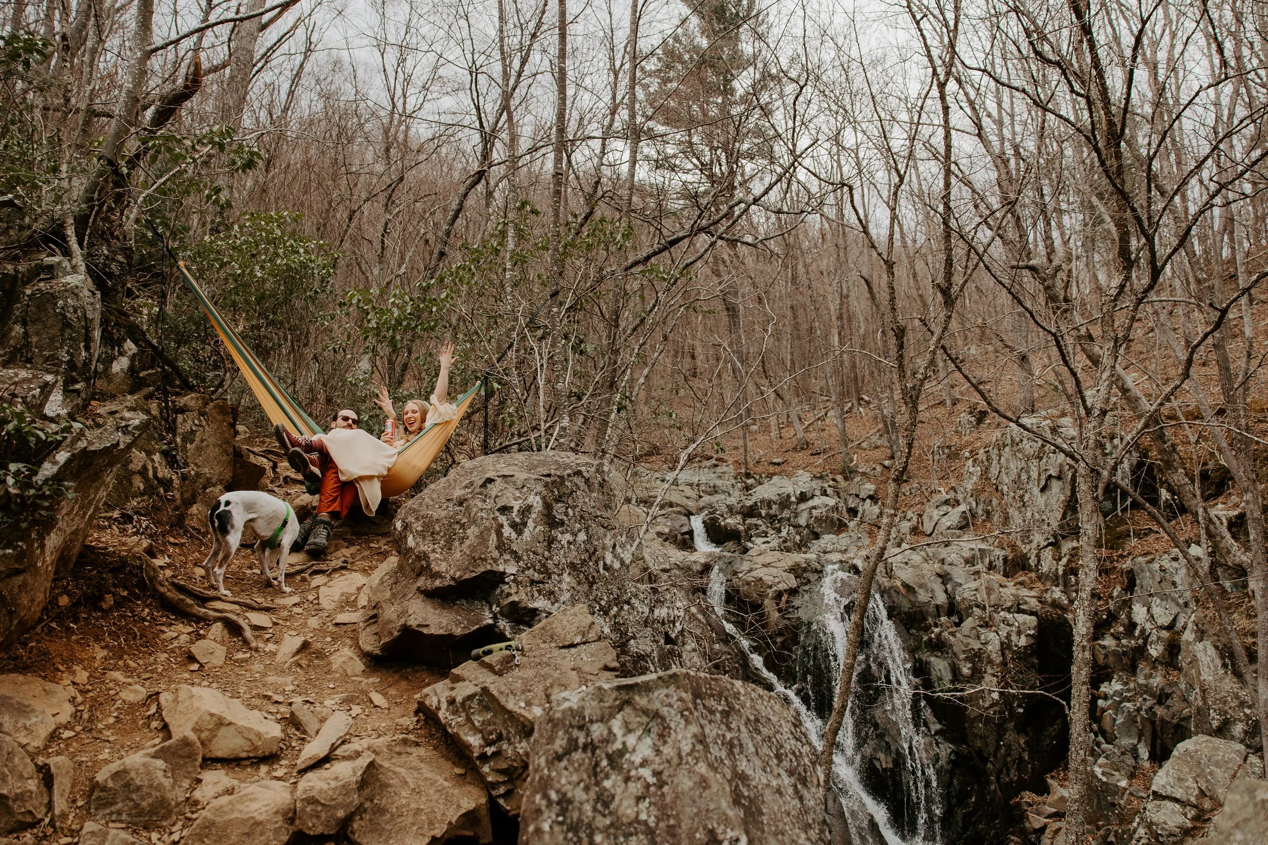 Couple relaxing in a hammock beside Rose River Falls in Shenandoah National Park during an adventurous waterfall elopement day