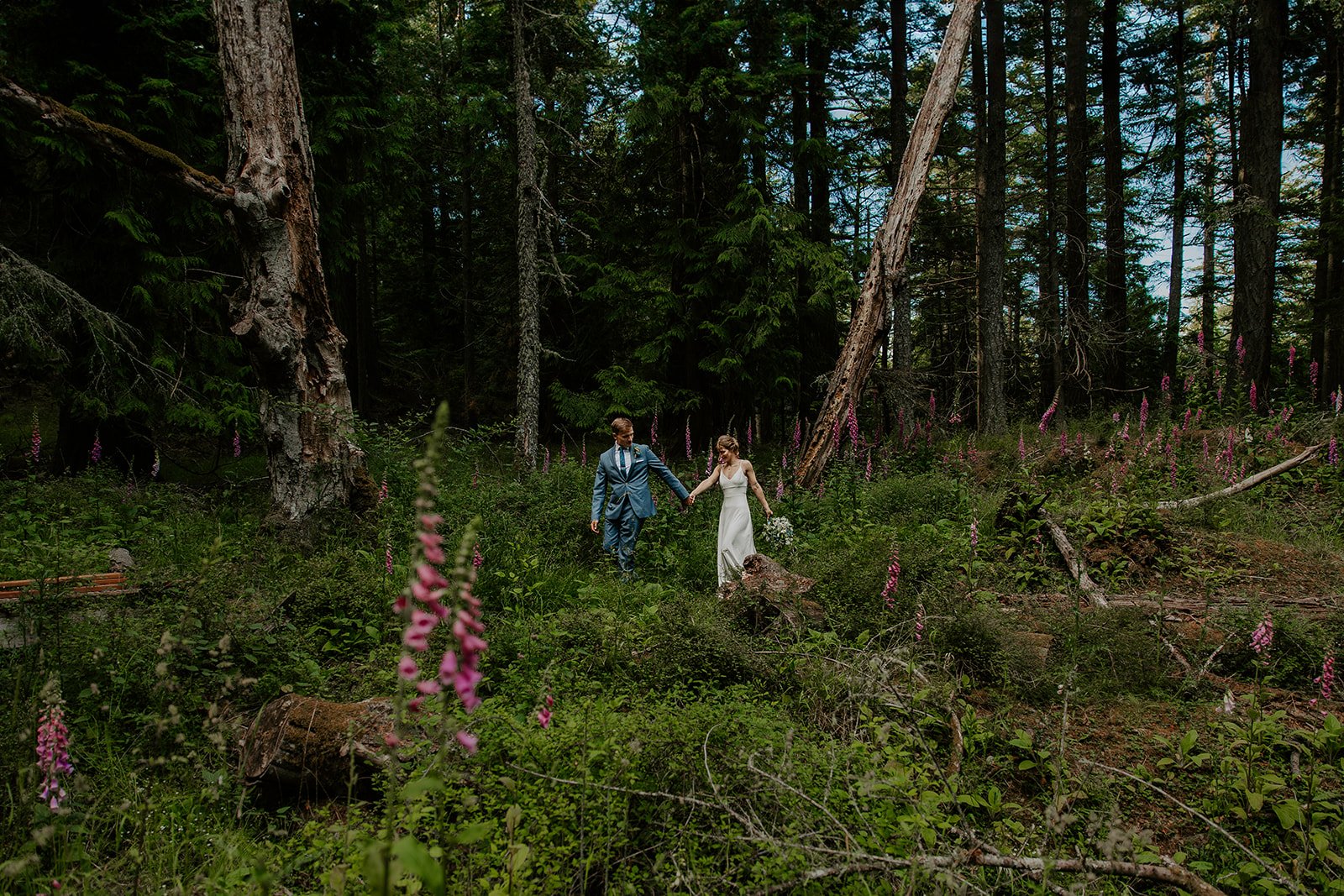 Couple walking through foxglove flowers in Moran State Park during Orcas Island elopement.
