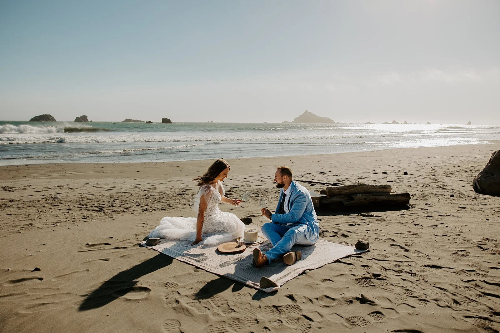 Newlyweds celebrating with cake and champagne at Pebble Beach near Jedediah Smith Redwoods State Park