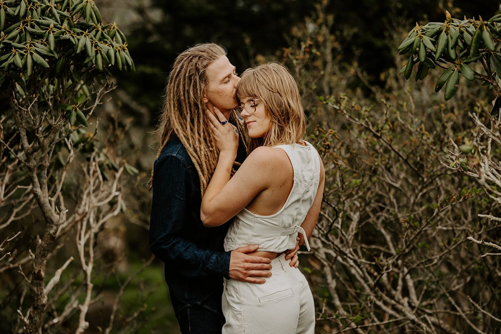 Couple embracing and kissing surrounded by rhododendron brush on an Appalachian ridgeline in West Virginia