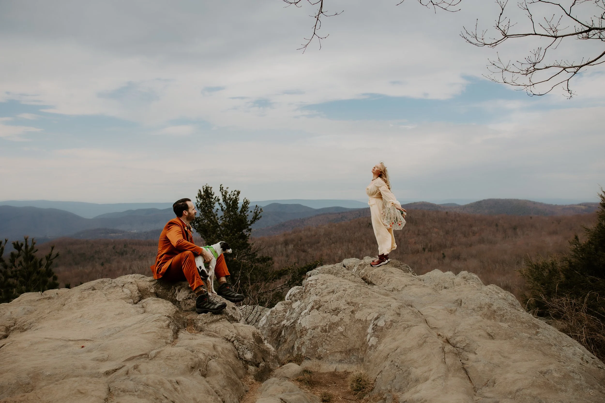 Couple relaxing on a rocky overlook with their dog during an adventure elopement