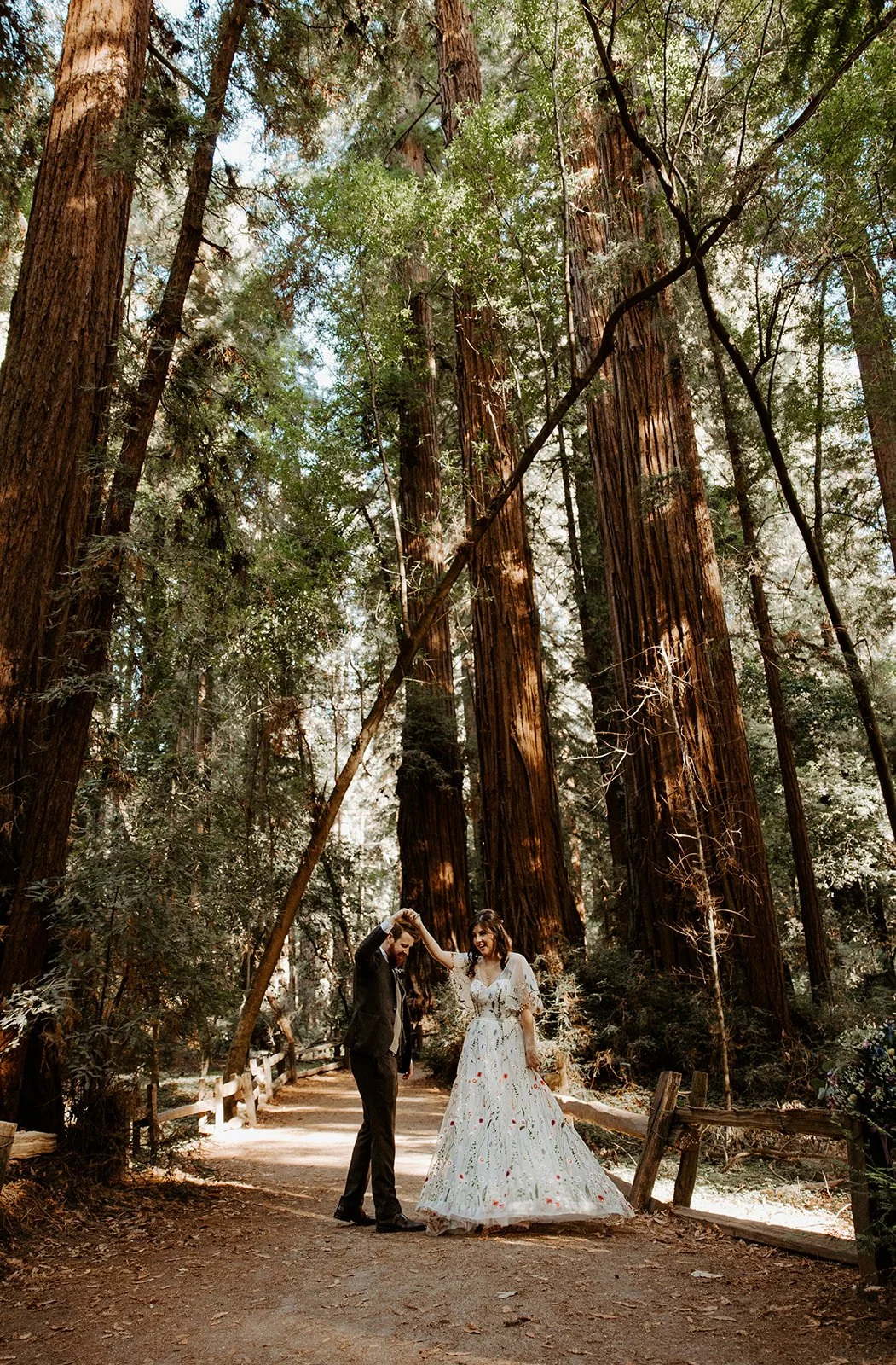 Couple dancing on the Redwood Grove trail at Henry Cowell Redwoods State Park, bride in a floral embroidered gown
