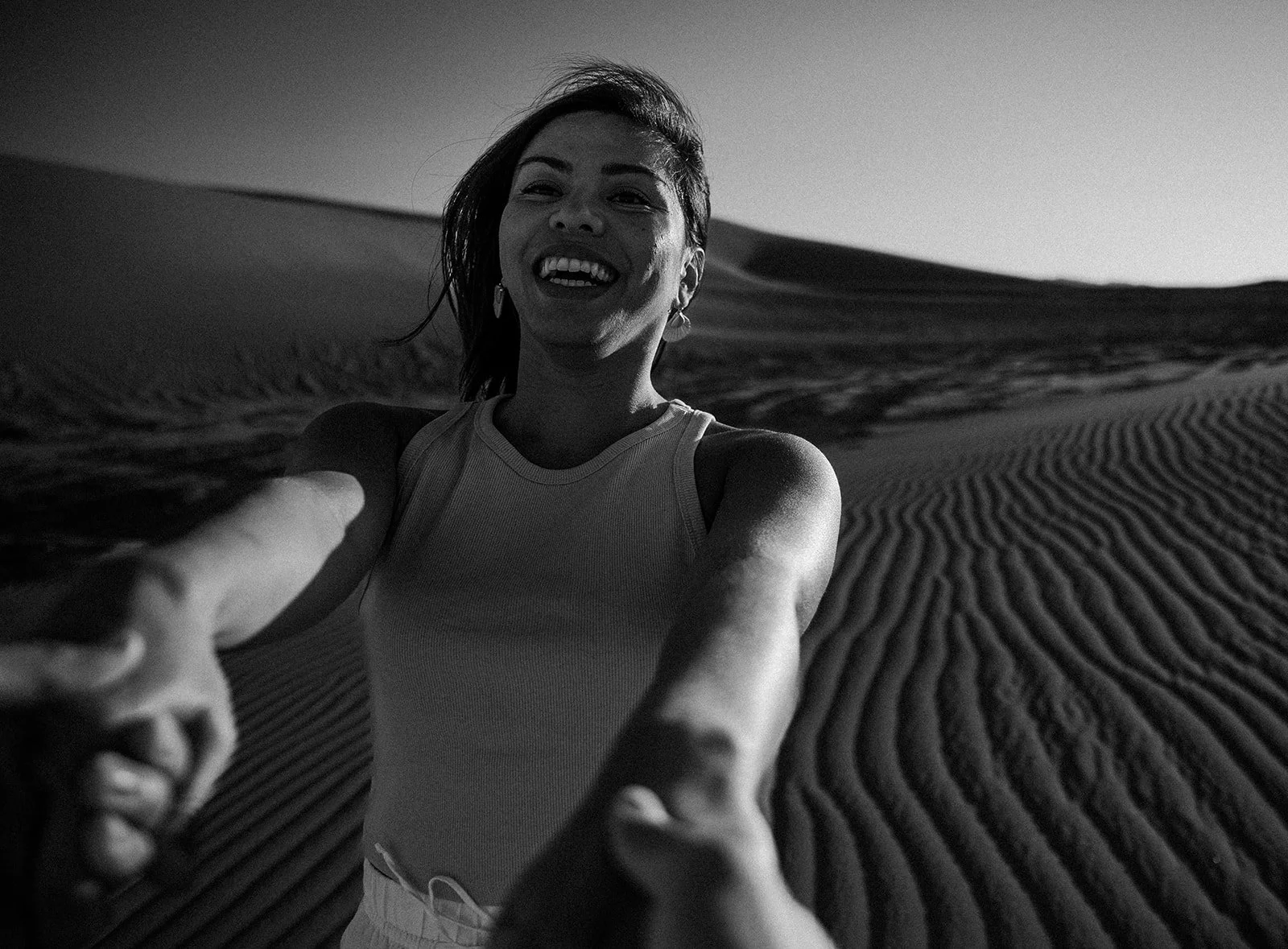 Smiling woman holding her partner's hands at Hugh T. Osborne Lookout in the Imperial Sand Dunes during sunrise engagement photos