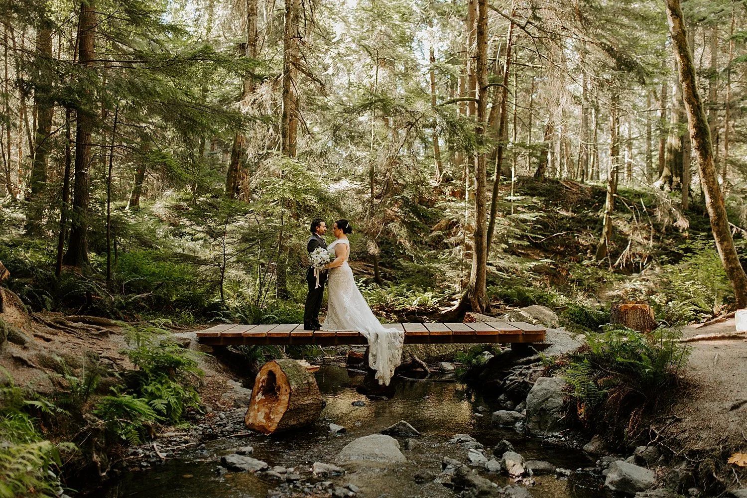 Bride and groom standing on wooden bridge near Cascade Falls on Orcas Island.