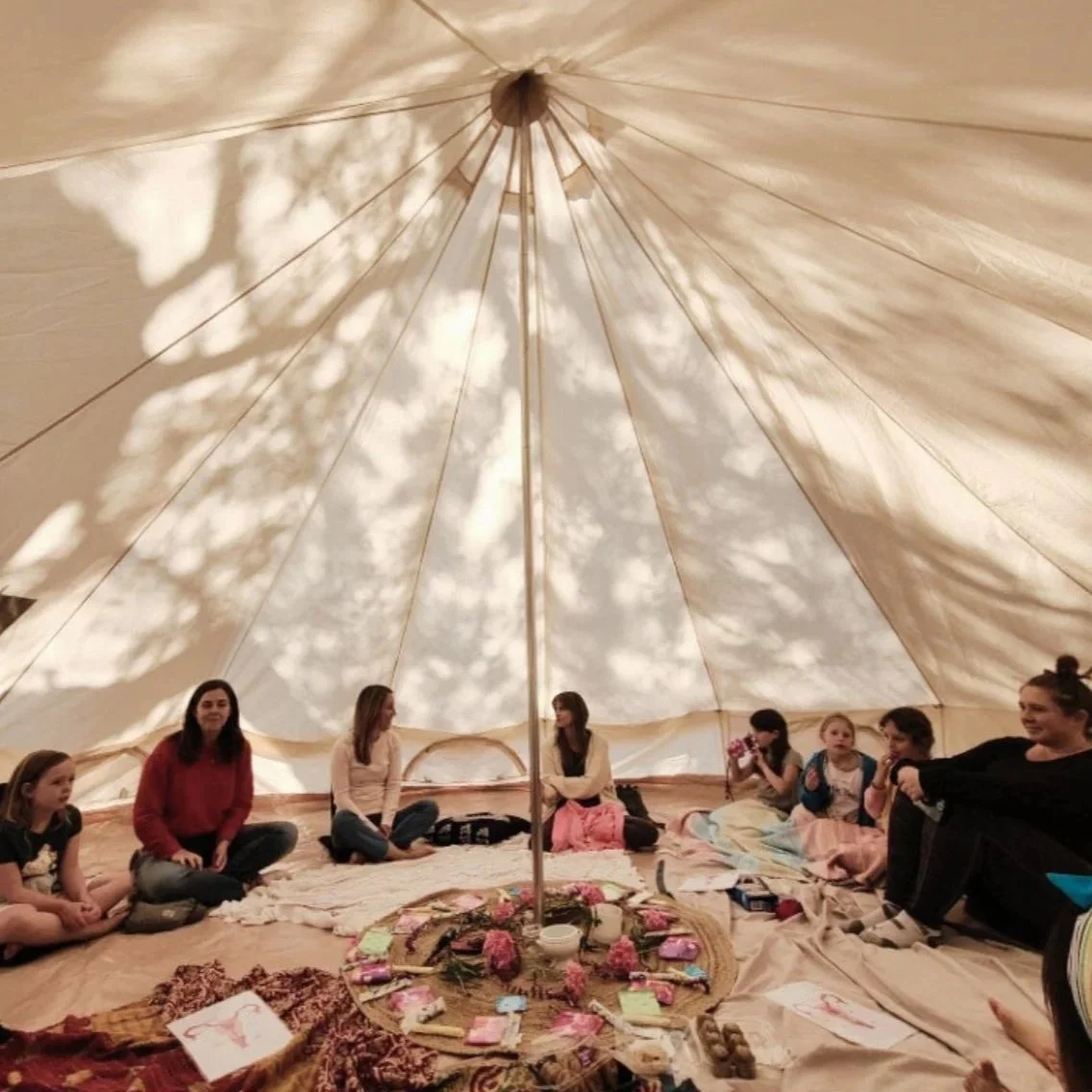 group of women and kids in circle in a tent