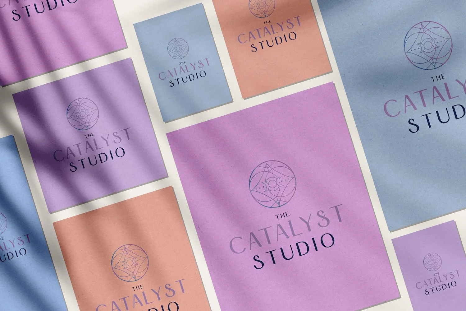 The Catalyst Studio logo with a crescent moon emblem printed on lavender, periwinkle, and coral papers