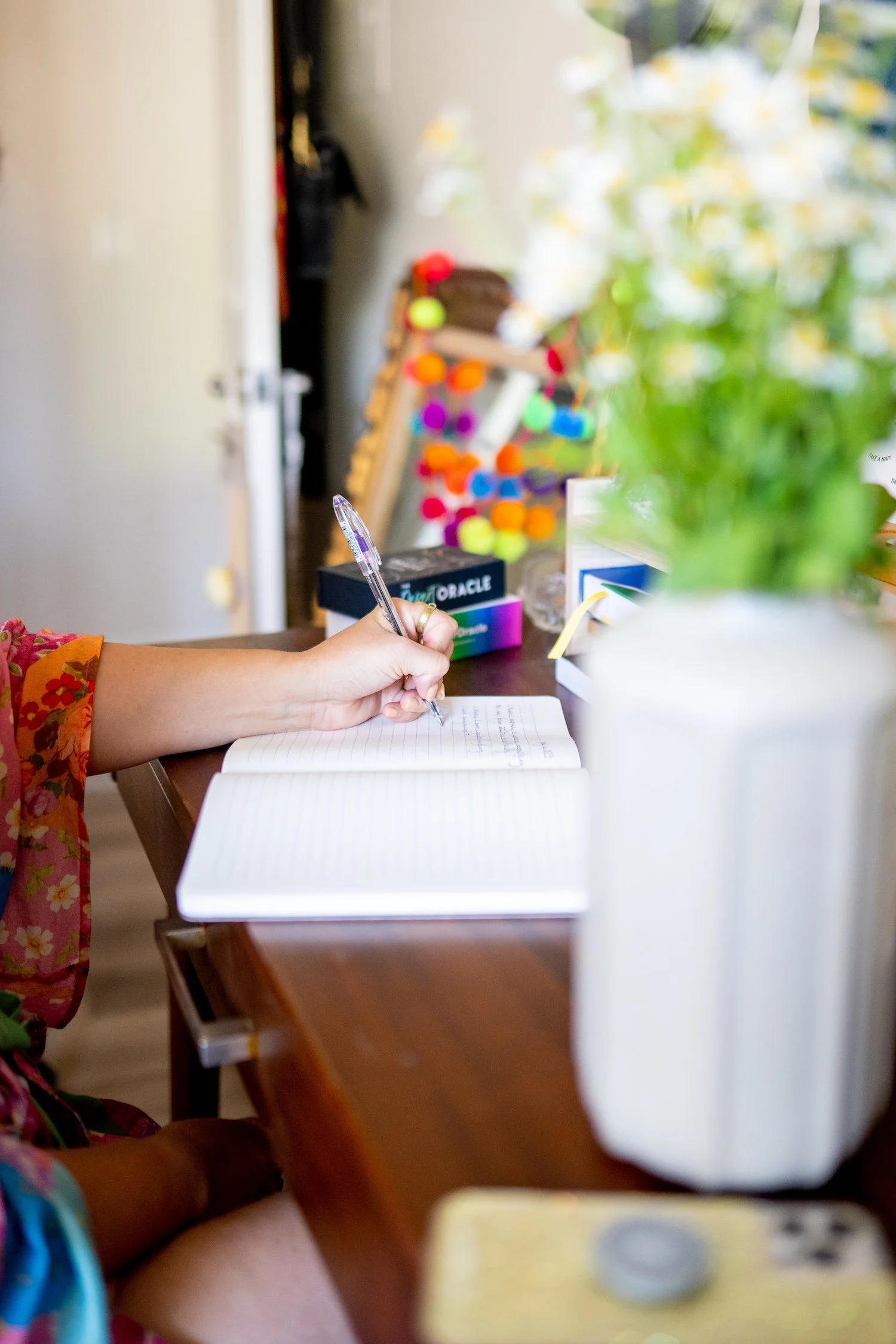 Alex writing brand insights in a notebook beside an oracle deck at her desk