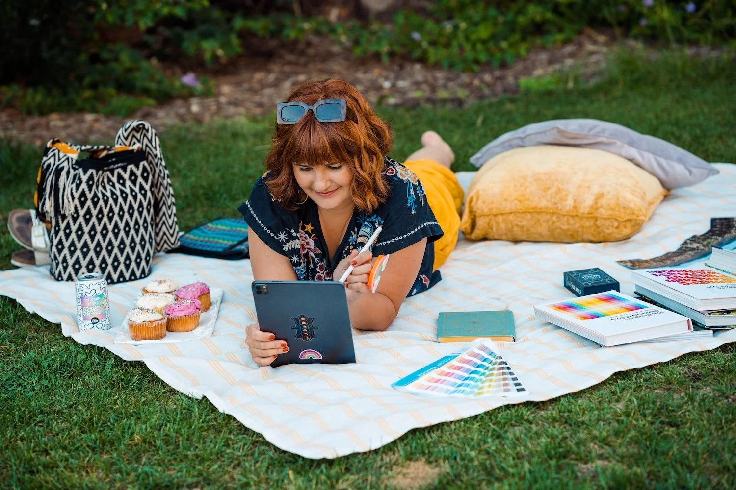 Alex designing on an iPad surrounded by color swatches, design books, and an oracle deck