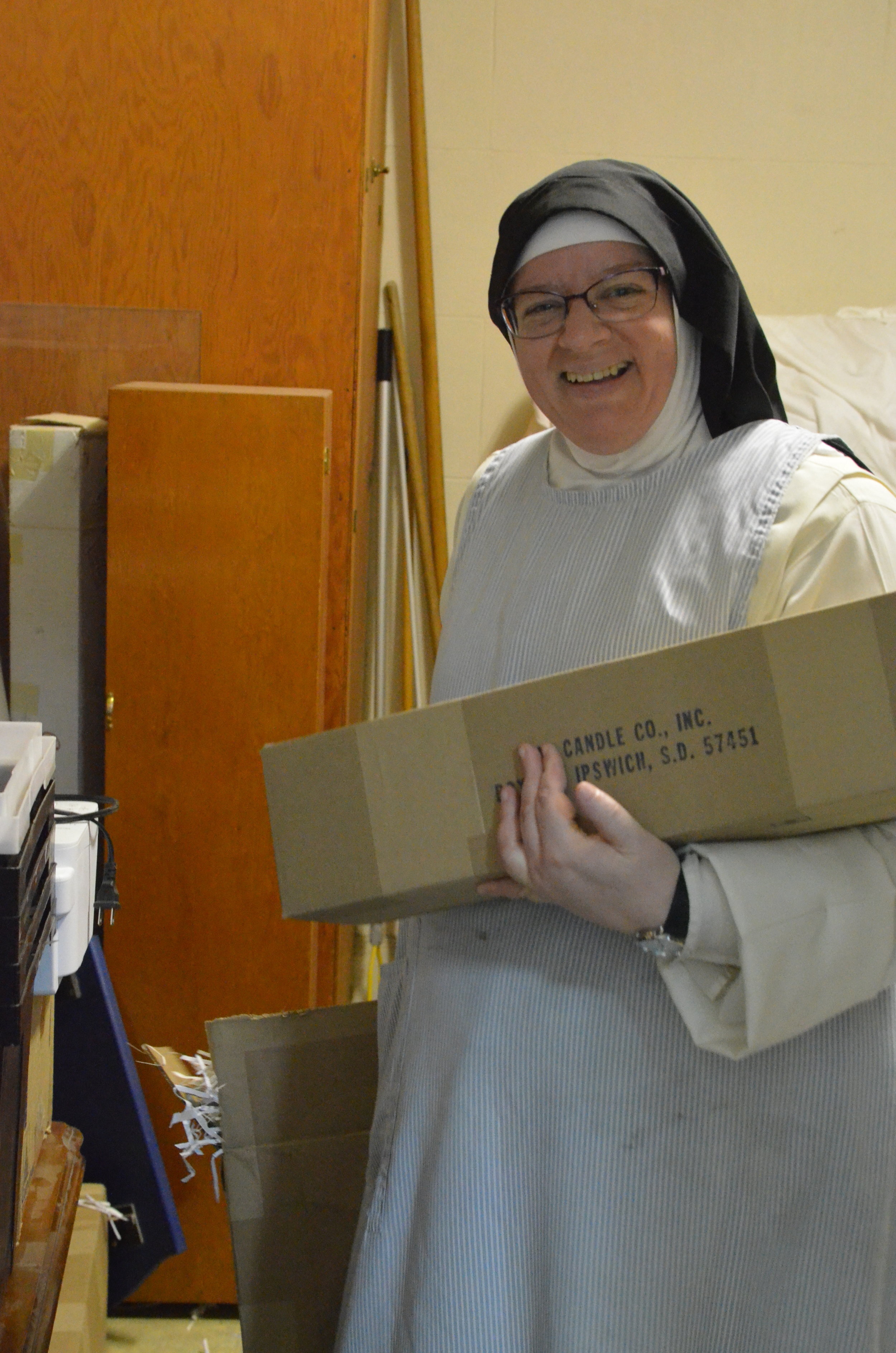 Sr. Judith Miryam, the sacristan, bringing up candles from the sacristy store room