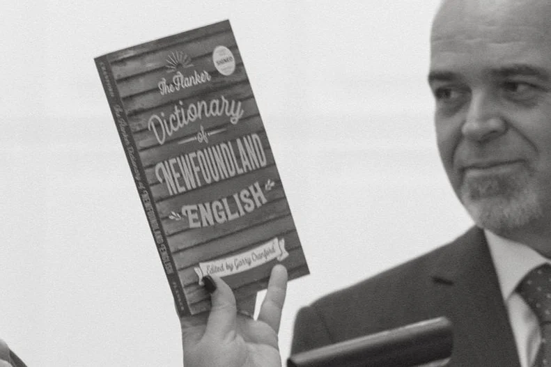 Woman holding The Dictionary of Newfoundland English while giving speech