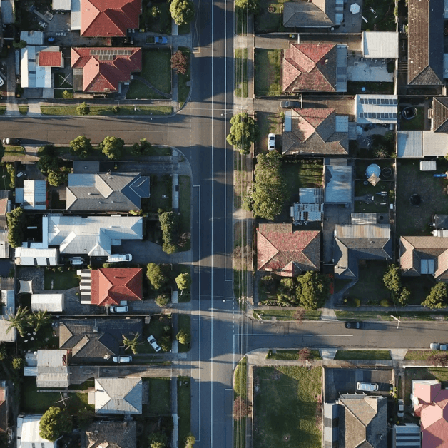 Aerial view of a residential neighborhood showing houses, trees, and streets with parked cars.