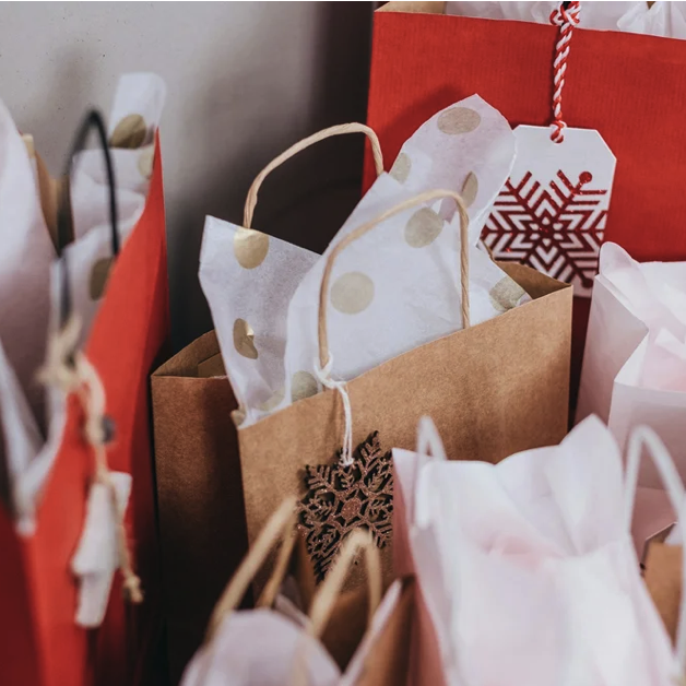 Close-up of gift bags with holiday-themed decorations and tissue paper, featuring red, white, and brown colors and snowflake ornaments.