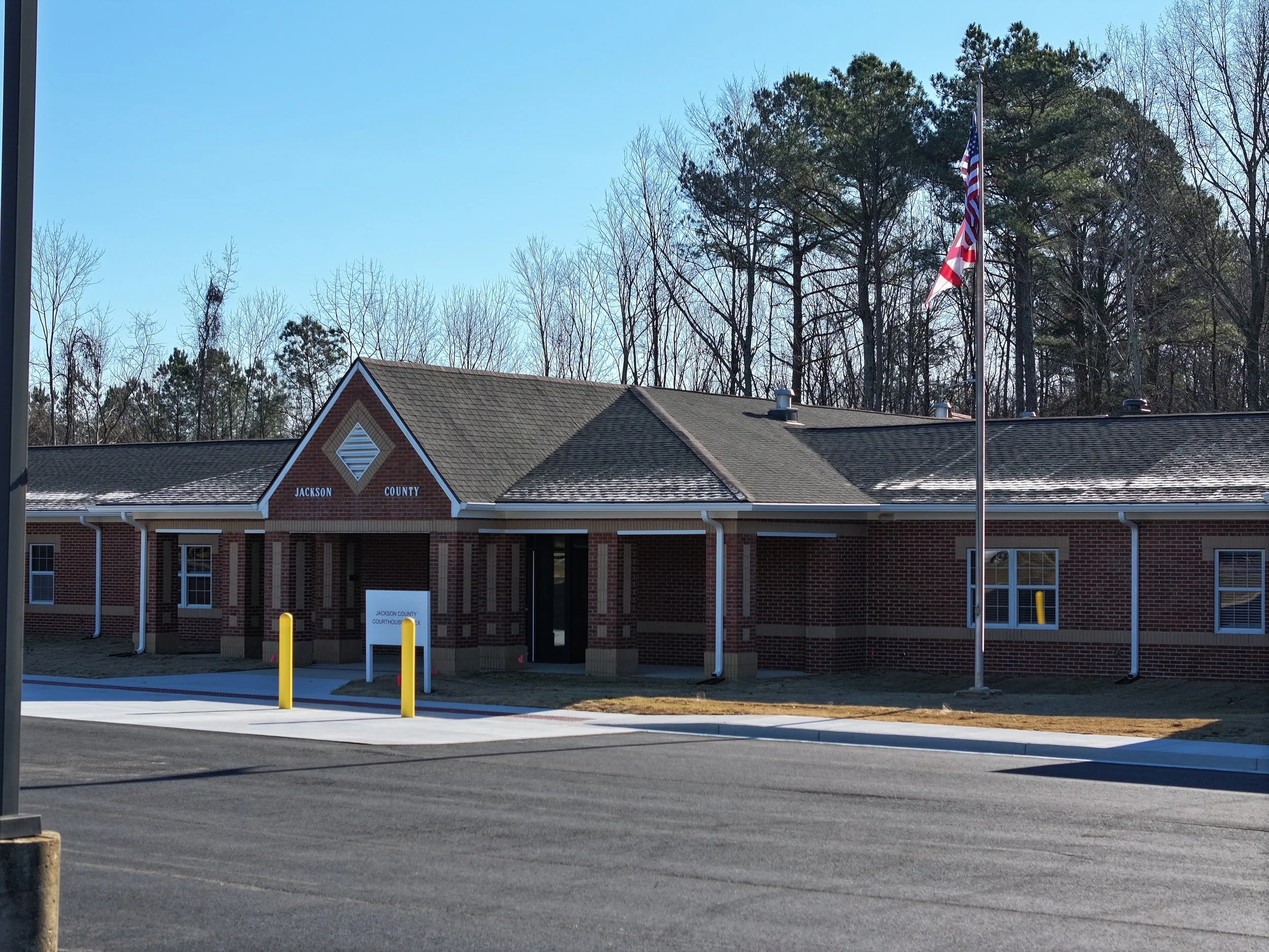 Jackson County Courthouse building with red brick exterior, American flag on flagpole, and trees in the background.