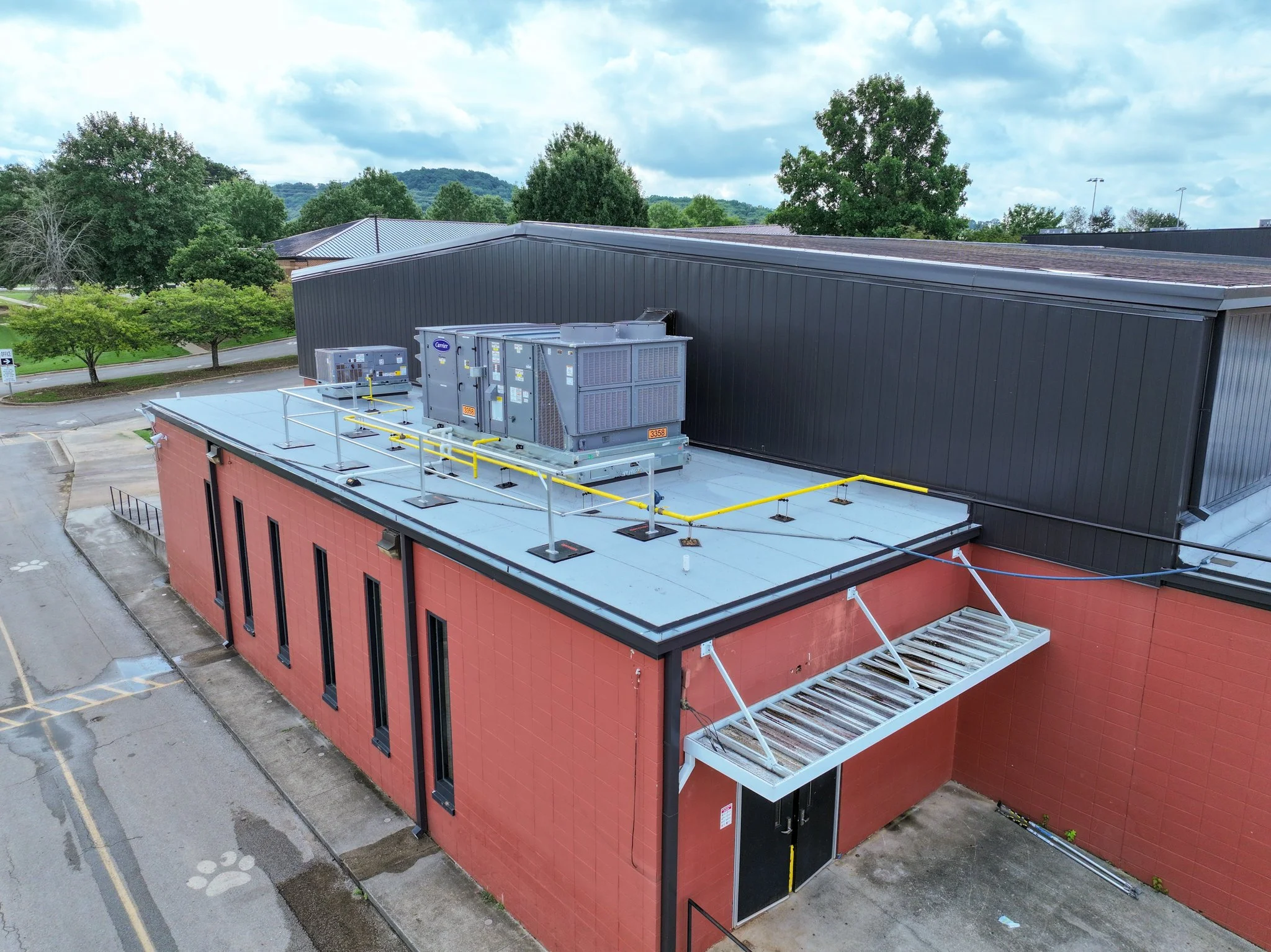Discovery Middle School with HVAC equipment on the roof, surrounded by trees and a parking lot, under a cloudy sky. Built by P&C Construction.