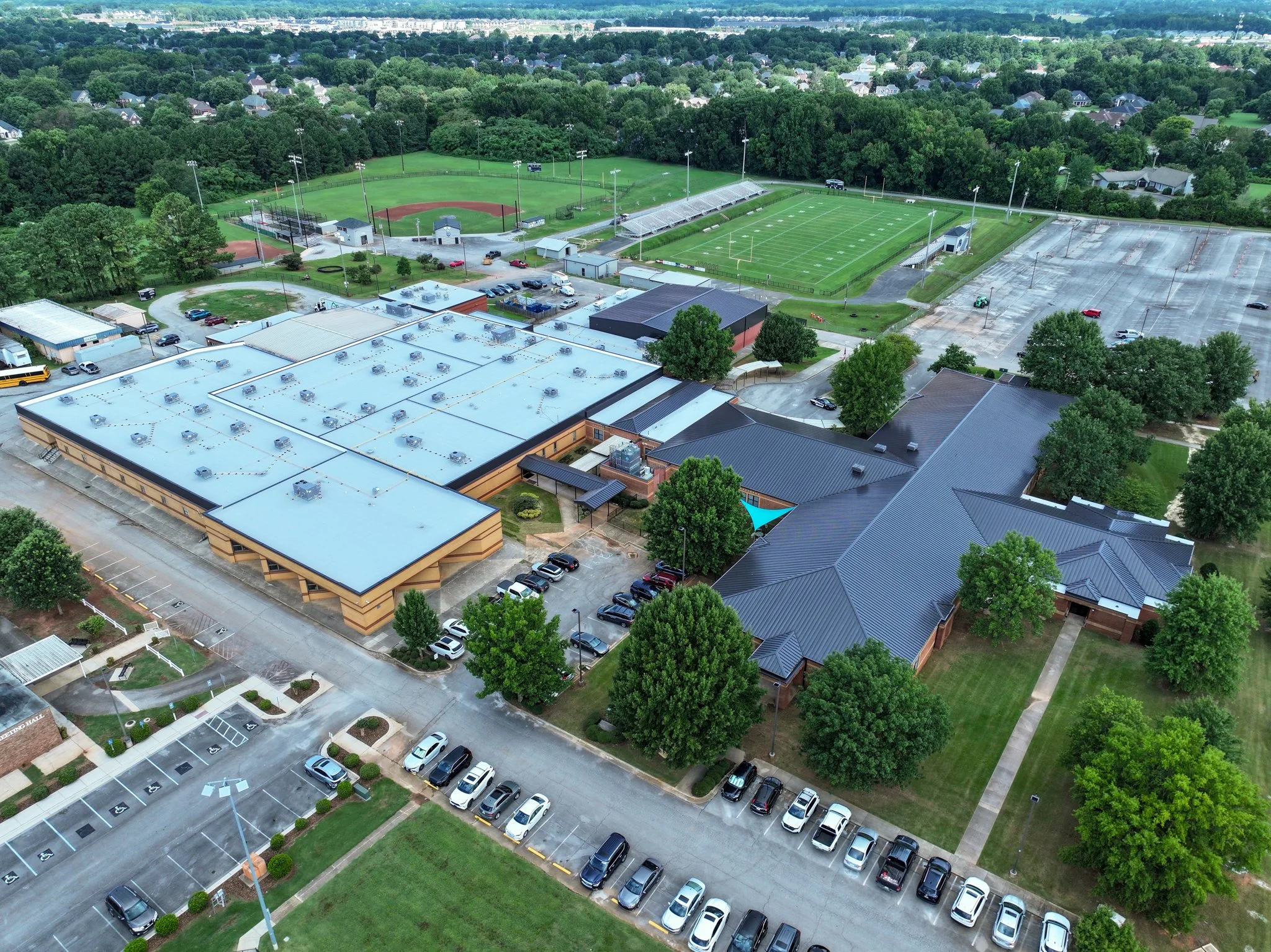 Aerial view of Discovery Middle School with a baseball field, soccer field, parking lots, and surrounding greenery.