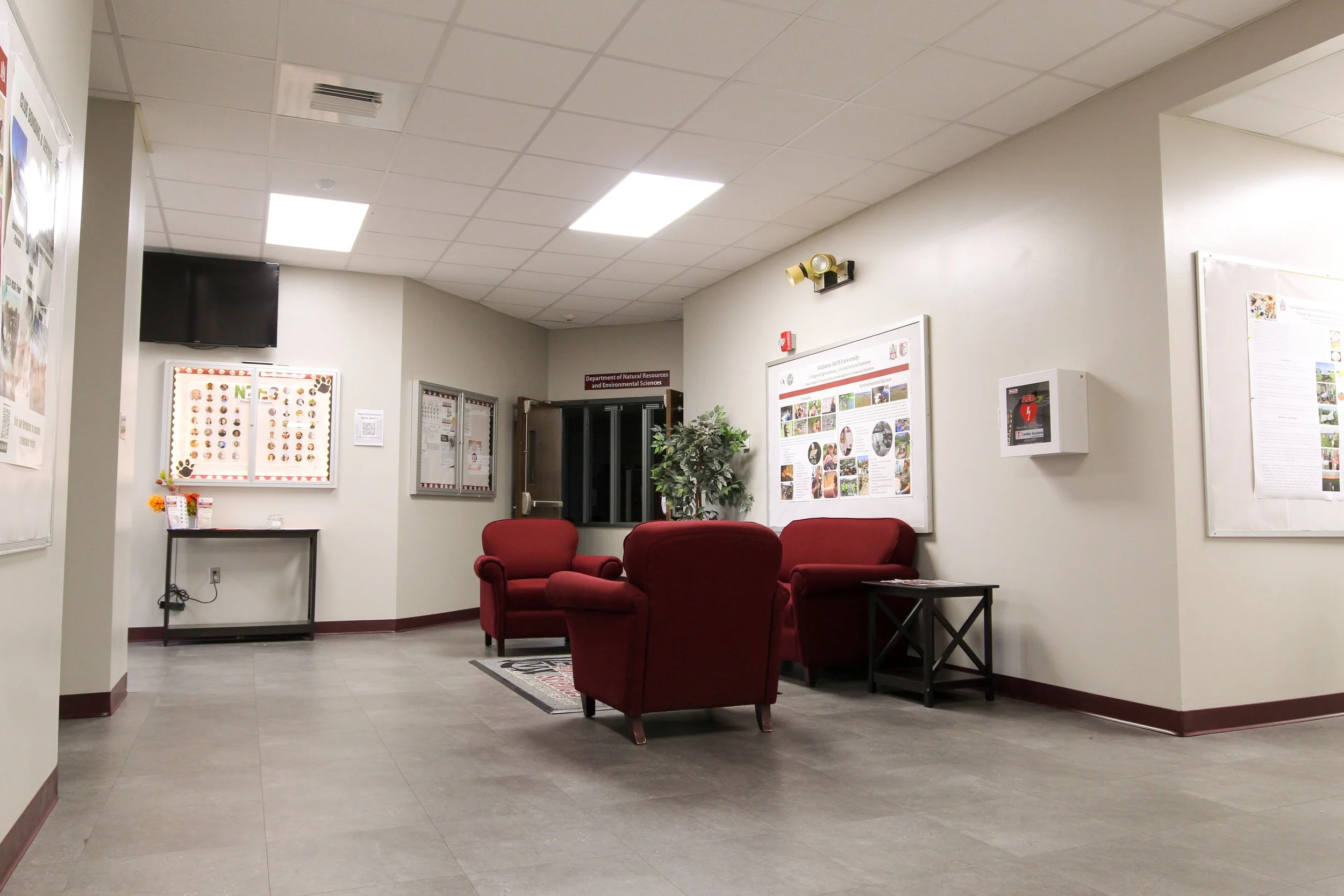 Empty waiting area with red chairs, wall displays, and informational posters.