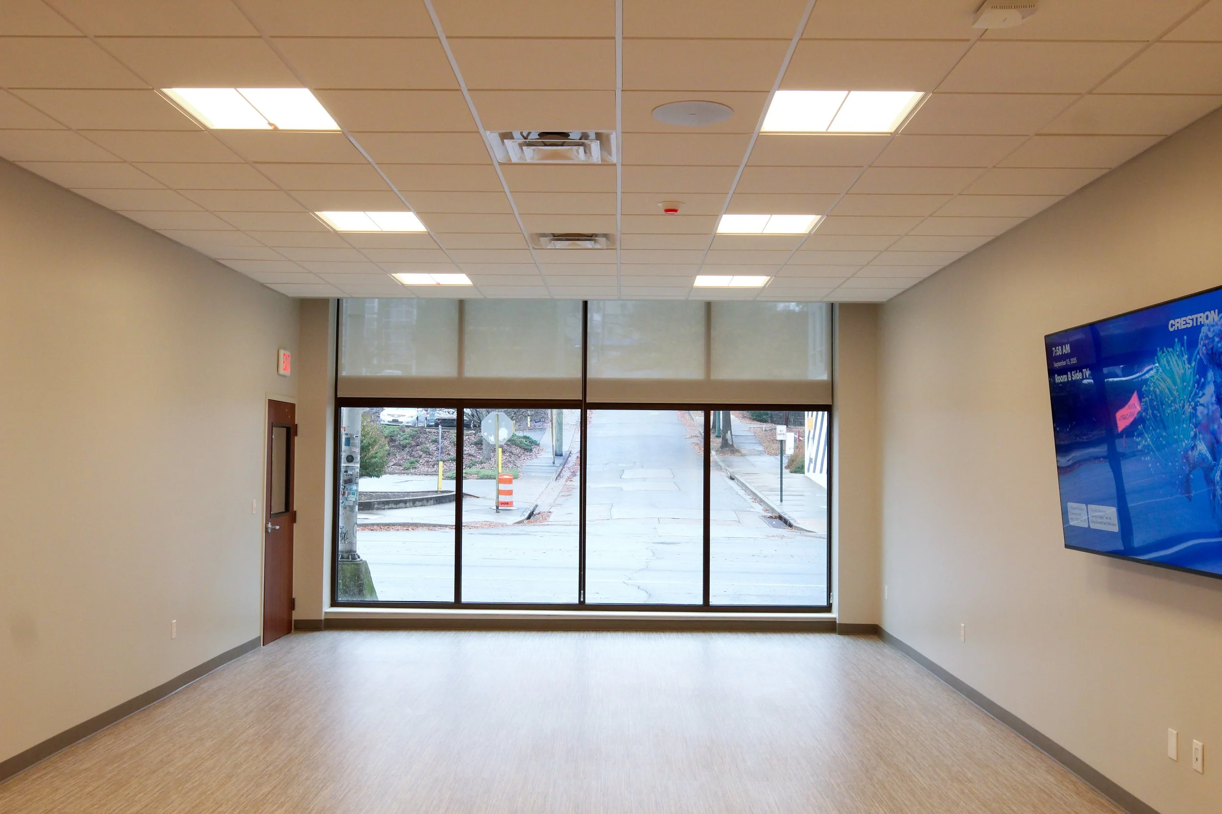 Empty room with large window and a wall-mounted TV.
