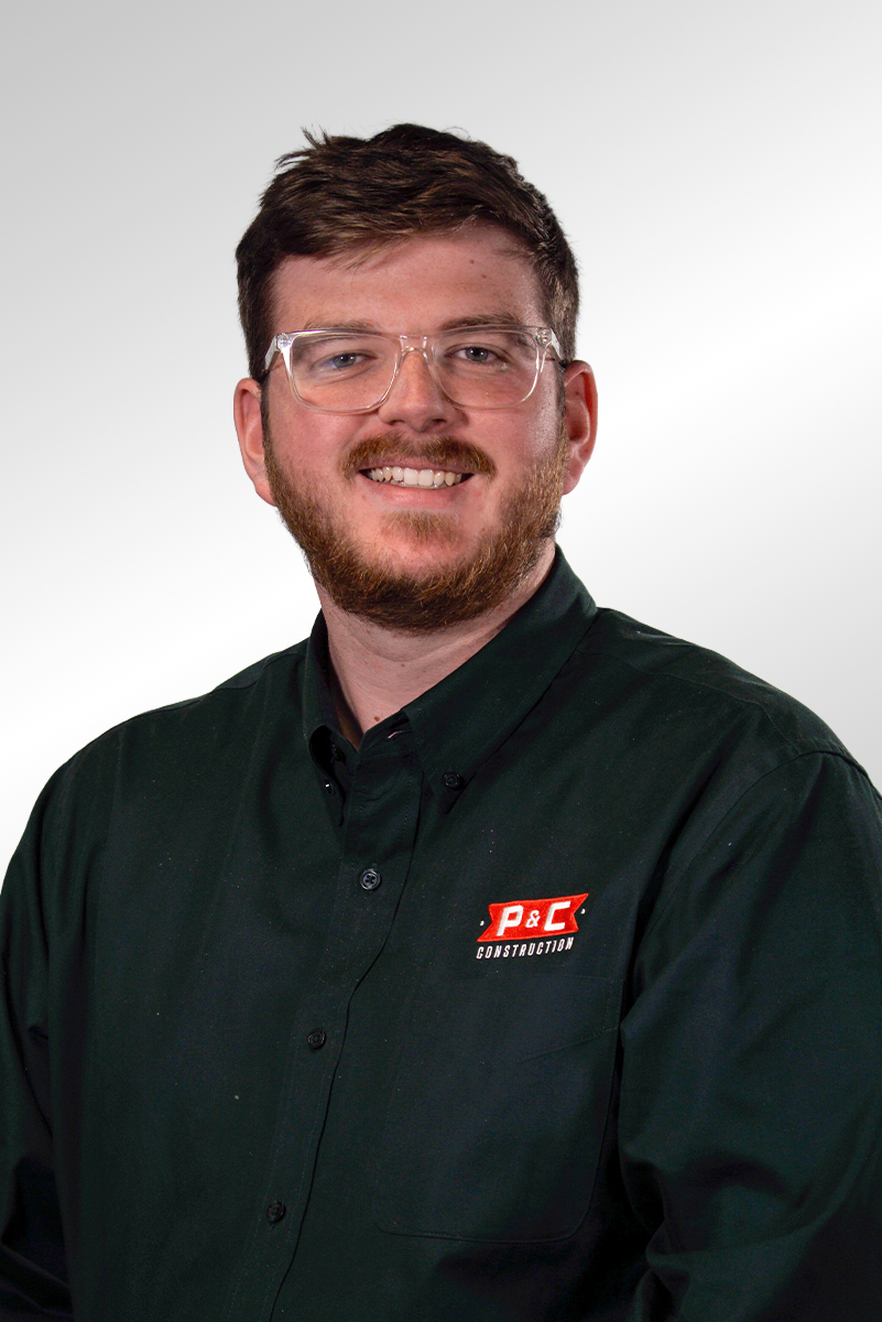 A man with glasses and a beard wearing a black collared shirt with a "P&C Construction" logo, smiling at the camera.