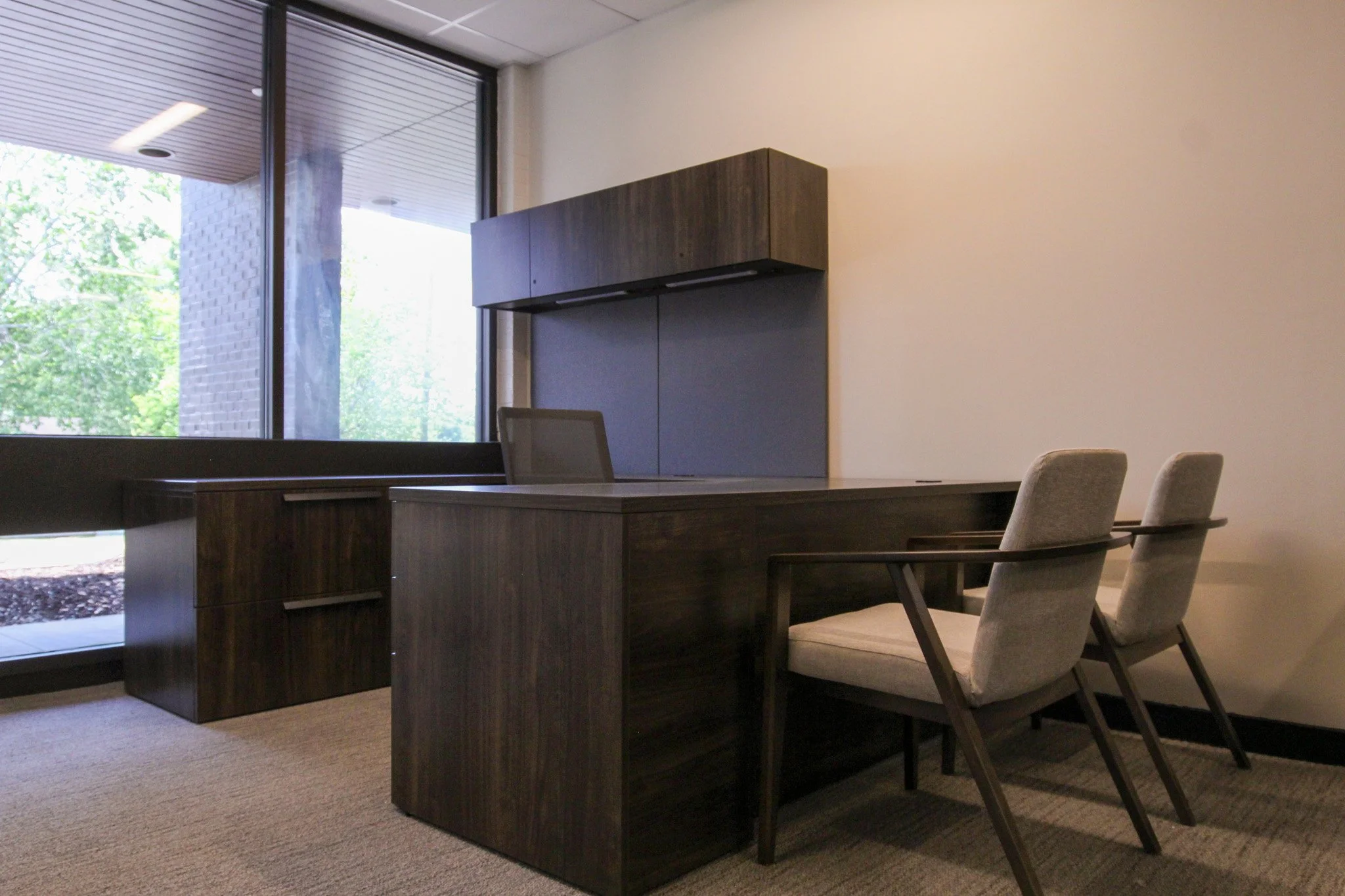 Office conference room of Simmons Bank in Athens, TN  with a desk, chairs, and window, with greenery outside.