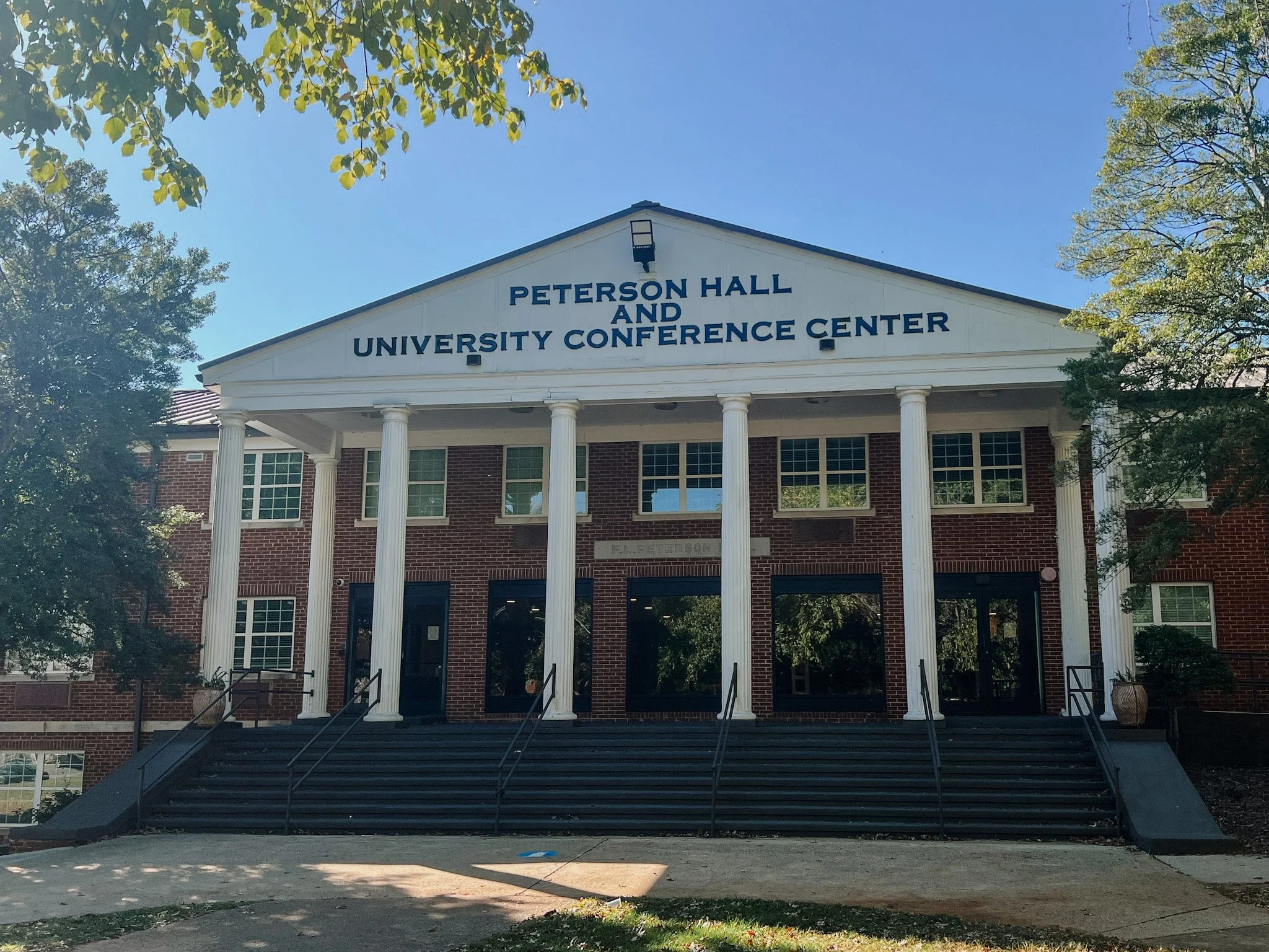 Front of Peterson Hall and University Conference Center, a brick building with white columns and stairs leading up to the entrance, surrounded by trees and a clear blue sky. Historic remodel by P&C Construction, Inc. - Chattanooga, Tn.