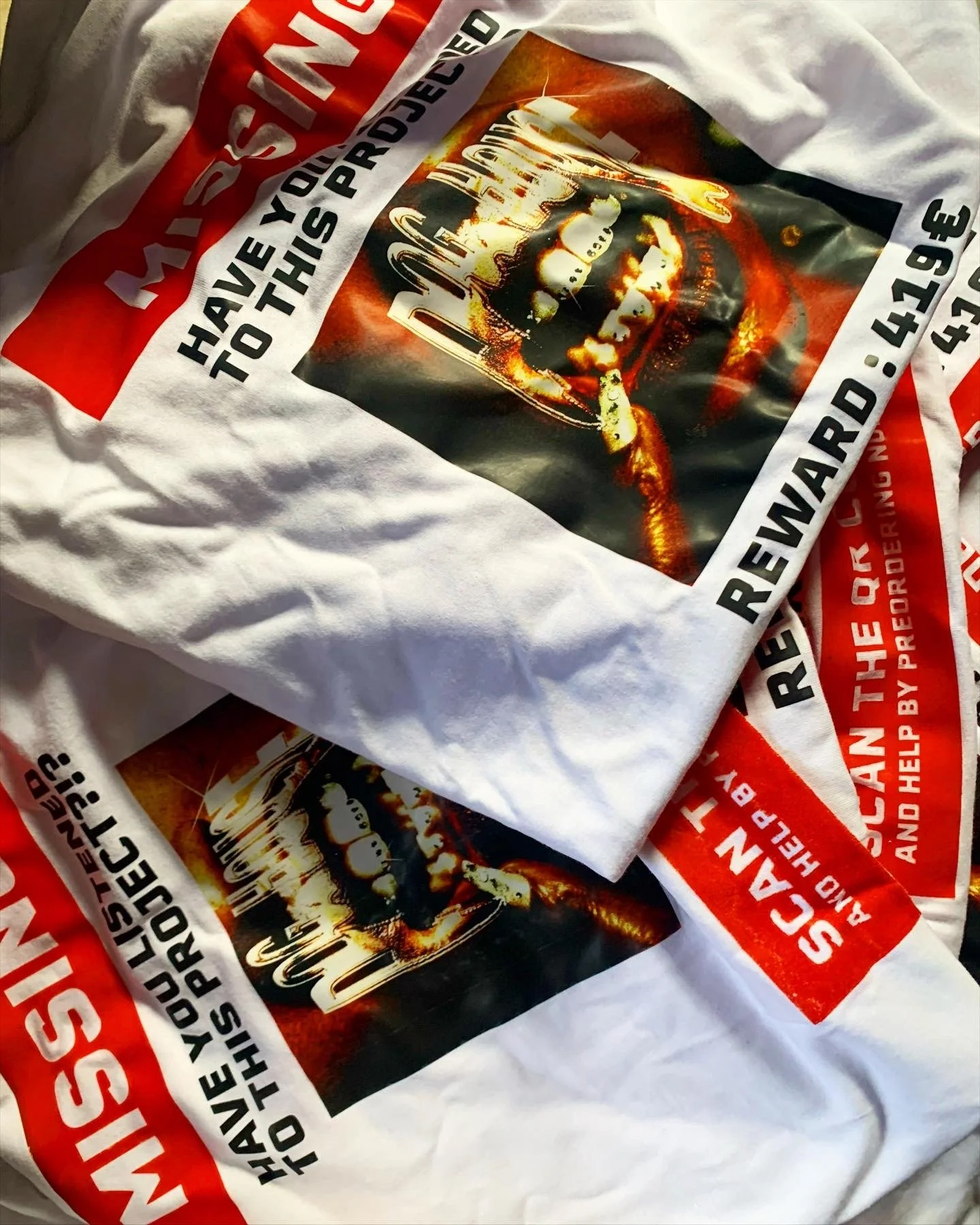 Two white T-shirts with a fire-themed skull logo and red, black, and white text urging to help veterans and rewarm.