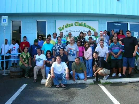 Group of people gathered outside a building with a sign that reads 'Ko'olau Clubhouse'.
