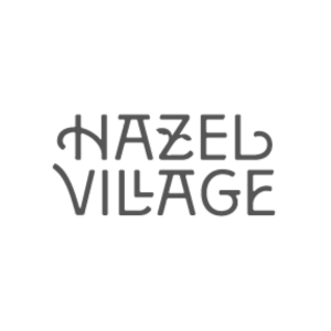 Logo with the text 'Hazel Village' in gray on a black background.