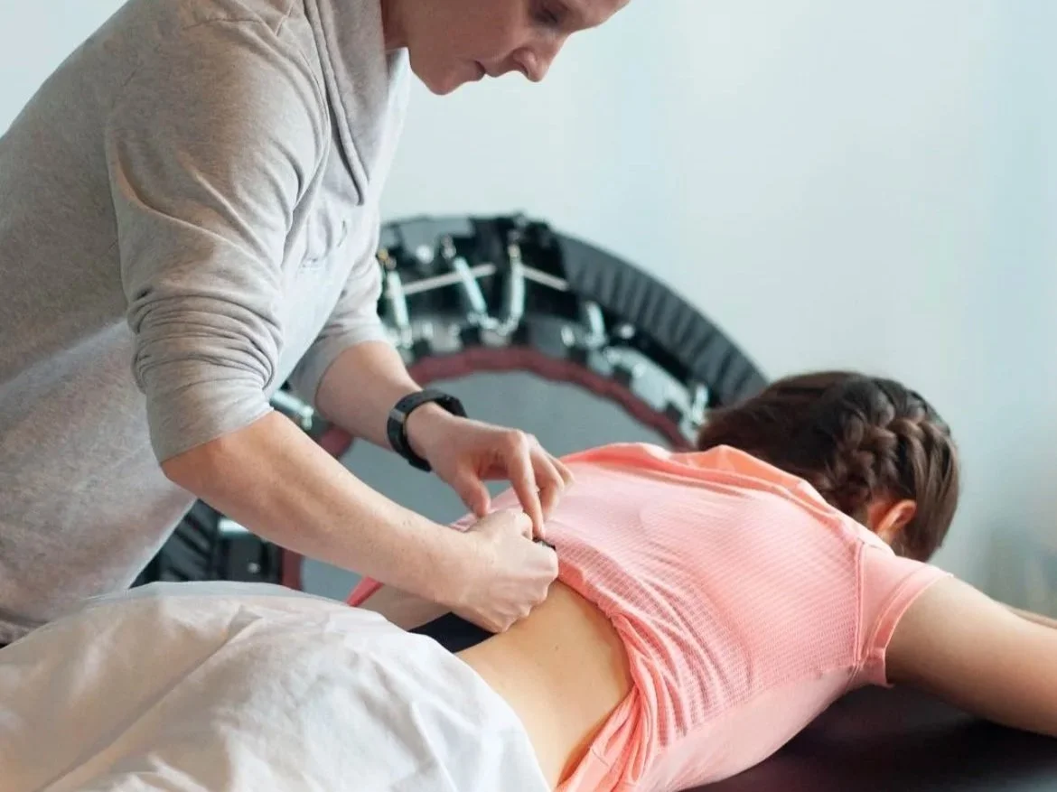 A healthcare professional preparing to give an injection to a woman lying on a bed or table.