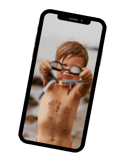 Child at the beach holds up goggles inside a smartphone display.