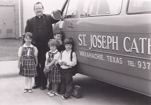 Father David Colello, some of the younger St Joseph School children and the school bus.