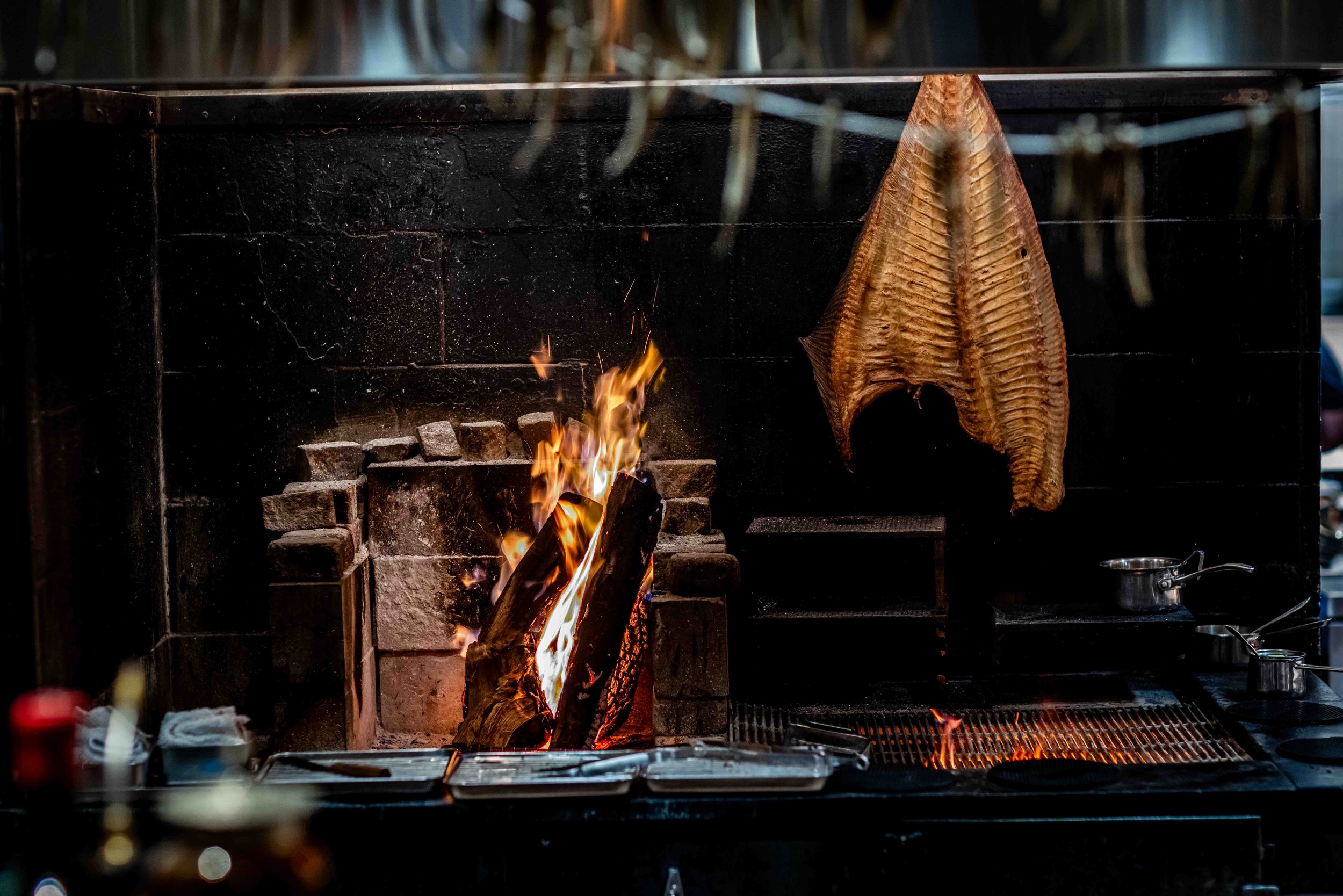 wood fired grill with fish hanging