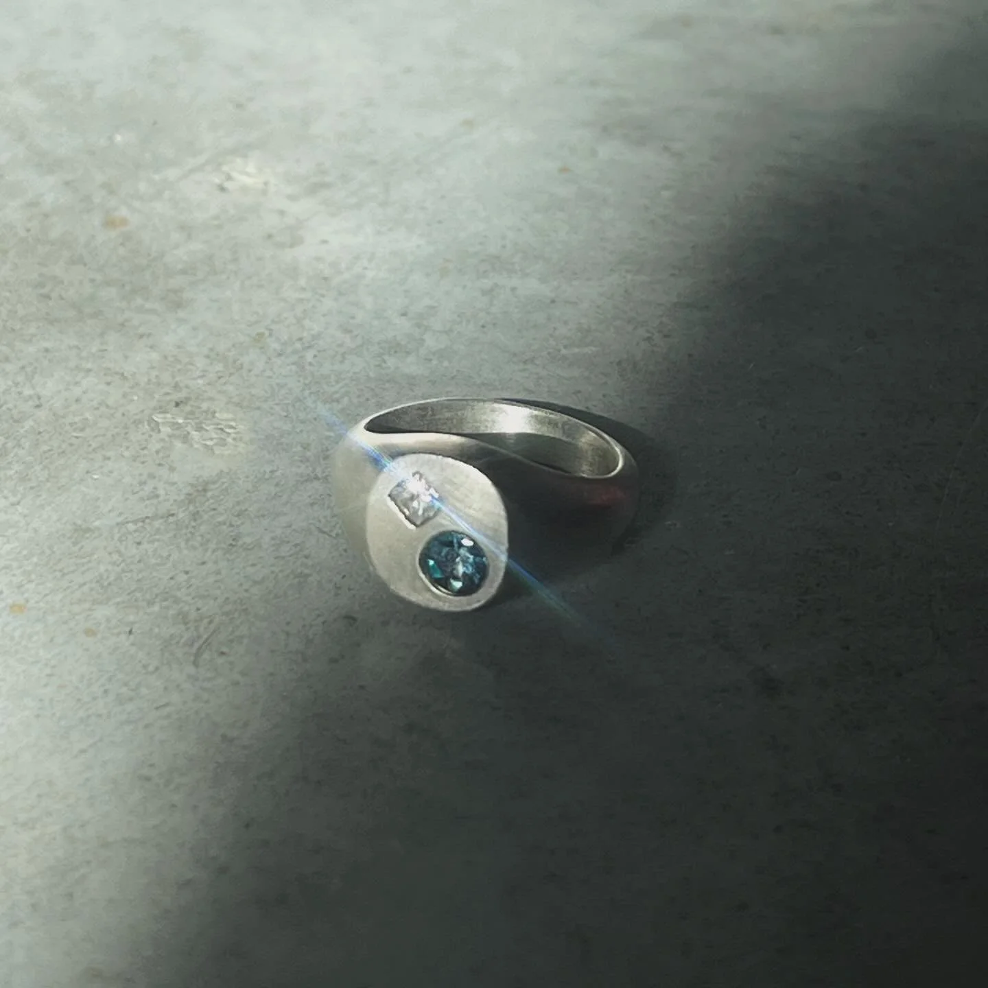 Parade signet.
Alexandrite and a square diamond set in brushed silver.

Alexandrite is one of the rarest gemstones. It&rsquo;s known for its natural color shift, appearing green in daylight and red or violet under warm light. The effect comes from th