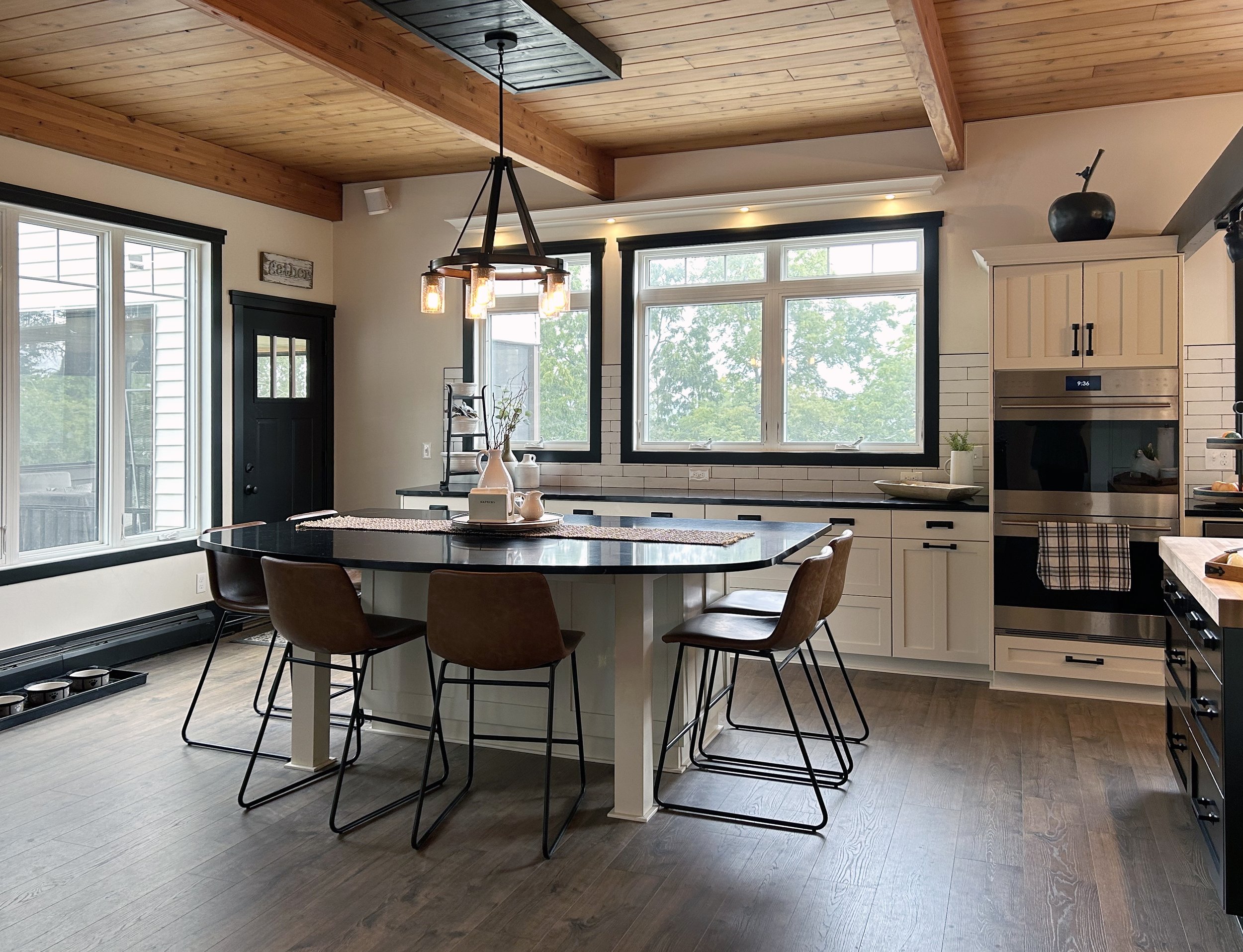 This is a modern farmhouse style kitchen and stunning wet bar. The kitchen has shaker style doors with a butcher block island top. There is a second island with extra seating that flows to the back patio. The wet bar has dark sleek cabinets with a be