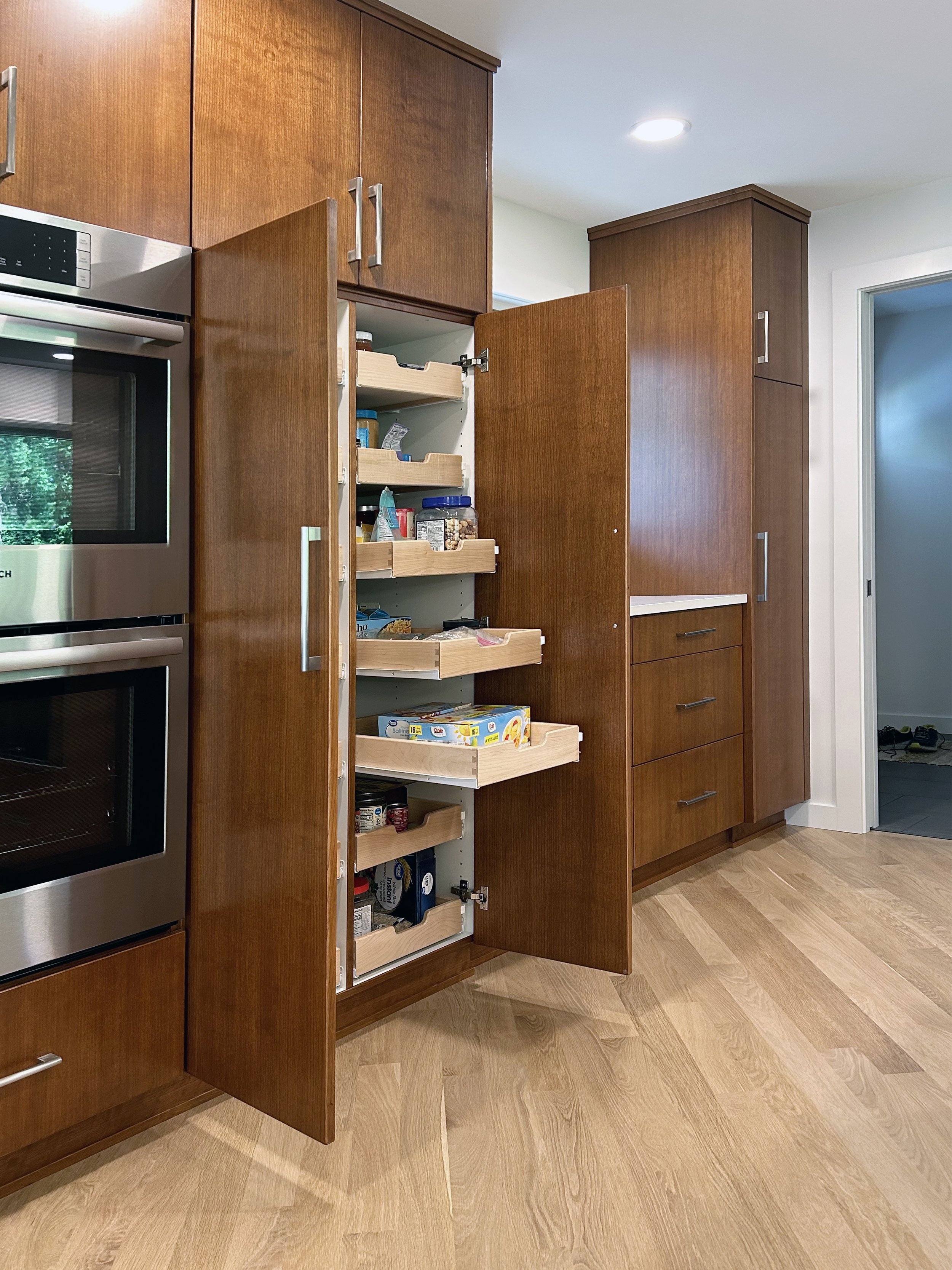 This full kitchen remodel is all cherry wood with slab doors in a full Midcentury Modern remodel. The slab doors are grain matched and the kitchen pantry has rollout drawers for easy access.