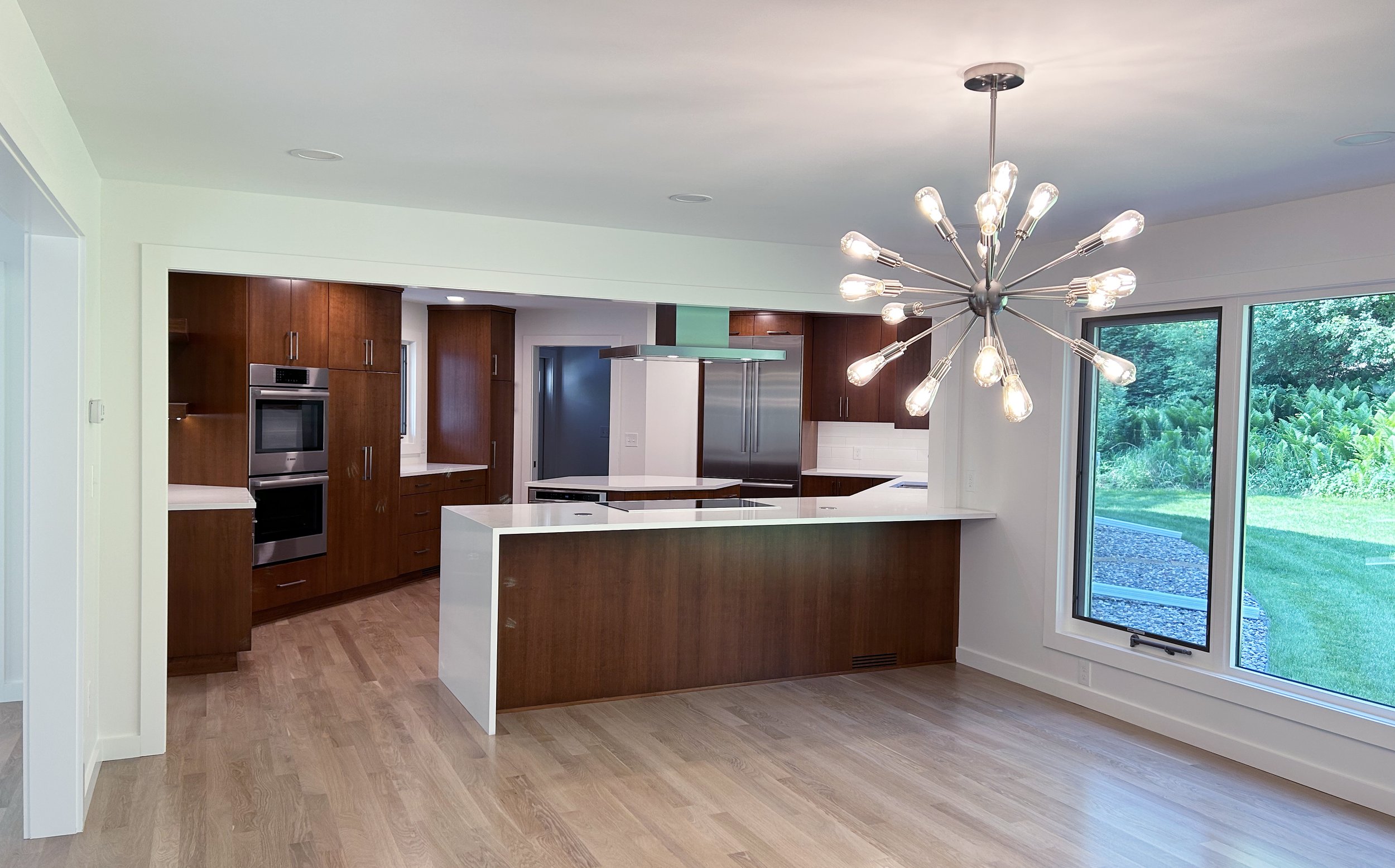 This full kitchen remodel is all cherry wood with slab doors in a full Midcentury Modern remodel. The slab doors are grain matched and the kitchen pantry has rollout drawers for easy access.